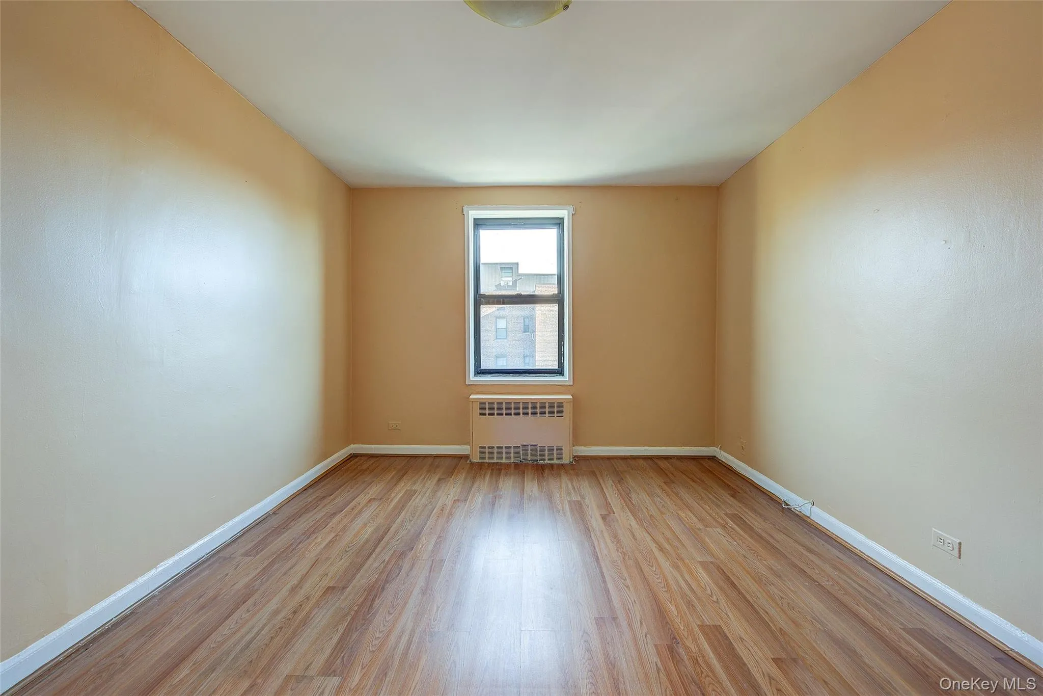 Spare room featuring light wood finished floors and radiator heating unit Spare room featuring light wood finished floors and radiator heating unit