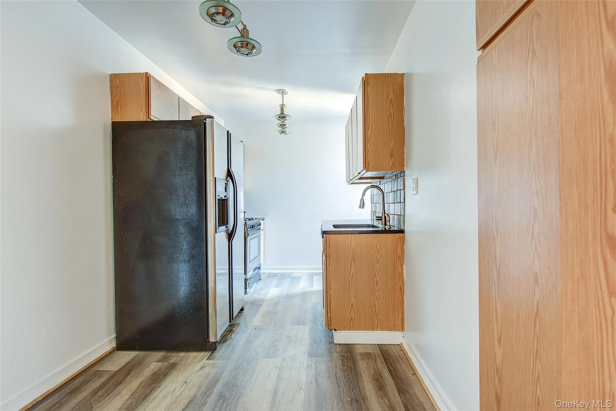 Kitchen with stainless steel appliances, light wood-type flooring, and light brown cabinets Kitchen with stainless steel appliances, light wood-type flooring, and light brown cabinets