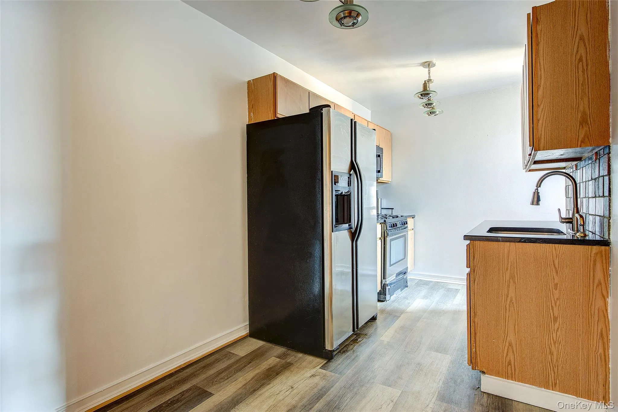 Kitchen featuring stainless steel appliances, light wood-style flooring, and pendant lighting Kitchen featuring stainless steel appliances, light wood-style flooring, and pendant lighting