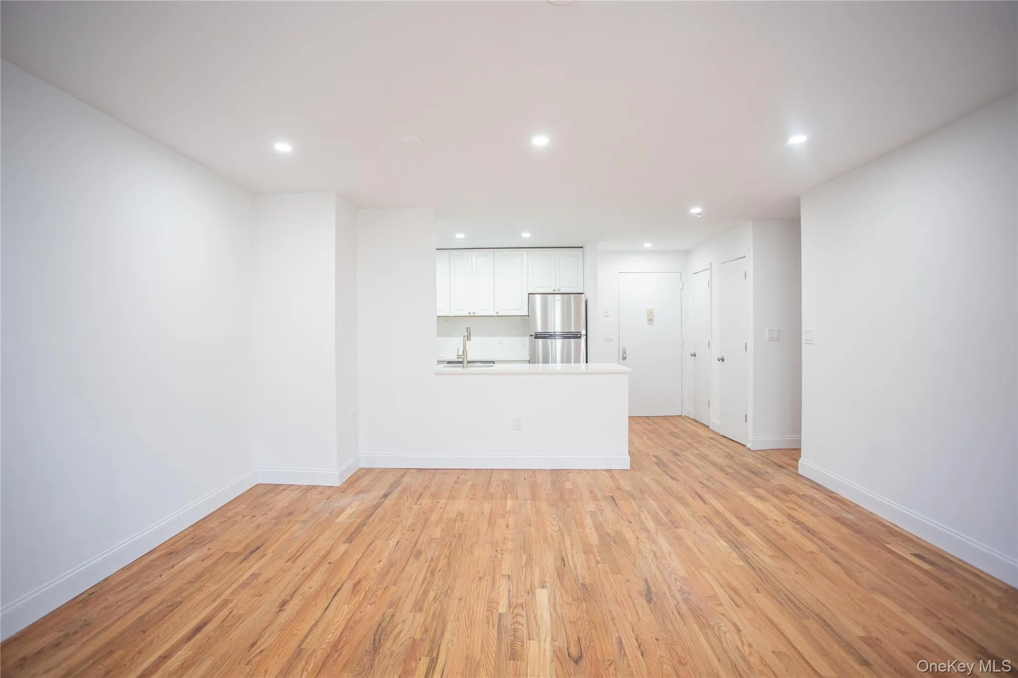 Unfurnished living room featuring light wood finished floors and recessed lighting Unfurnished living room featuring light wood finished floors and recessed lighting