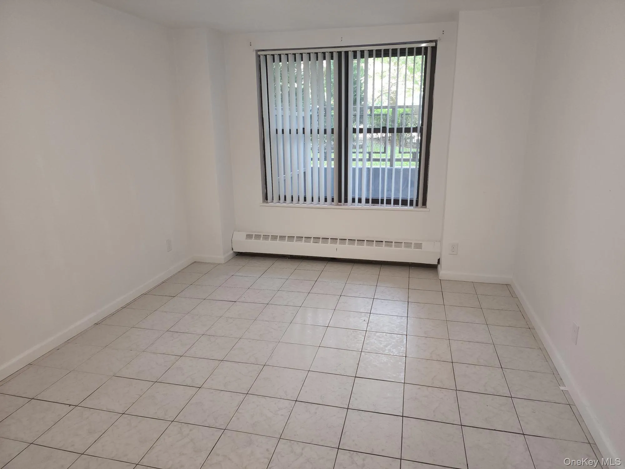 Unfurnished room featuring baseboard heating and light tile patterned floors Unfurnished room featuring baseboard heating and light tile patterned floors