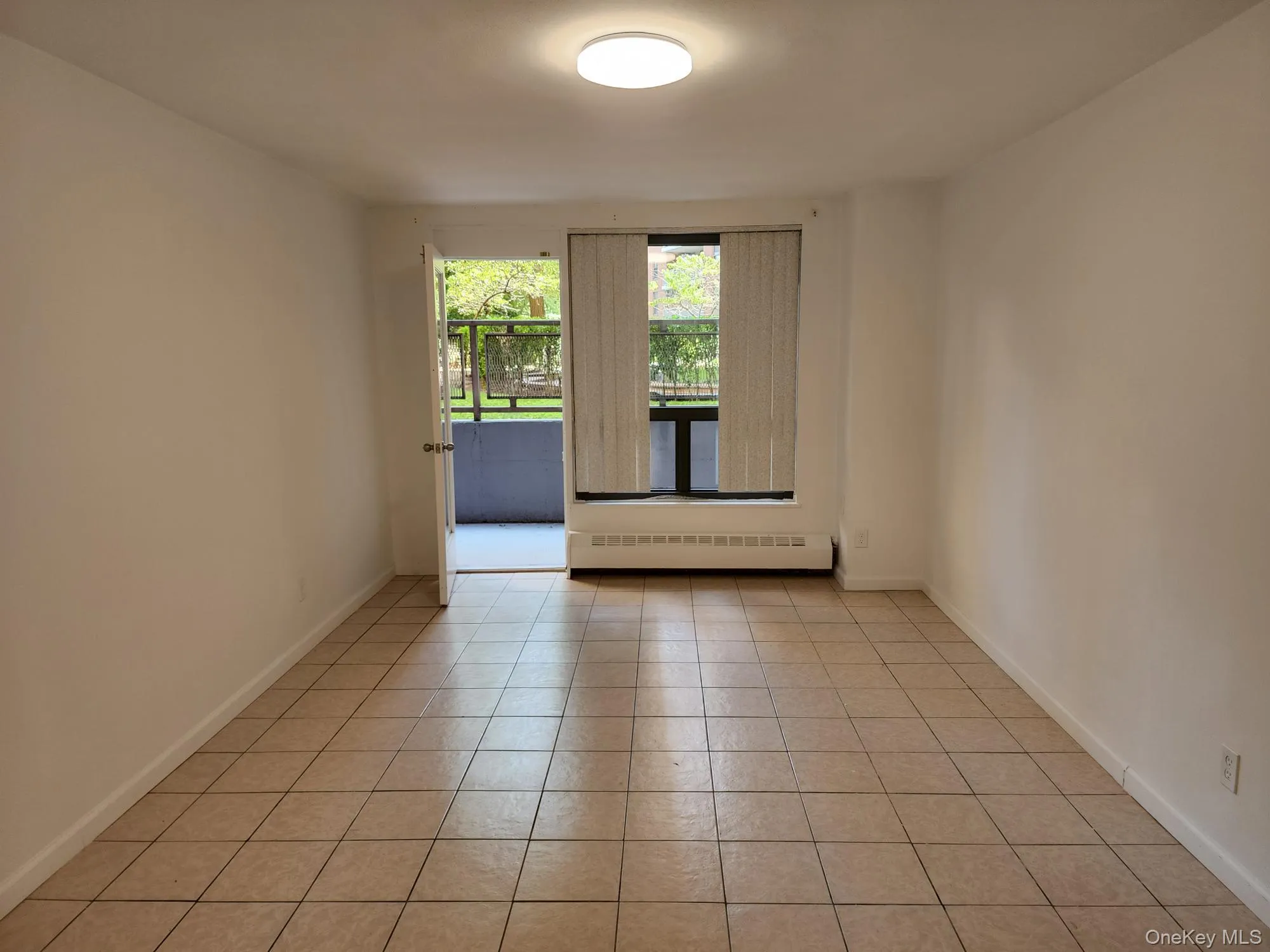 Unfurnished room featuring a baseboard heating unit and light tile patterned flooring Unfurnished room featuring a baseboard heating unit and light tile patterned flooring