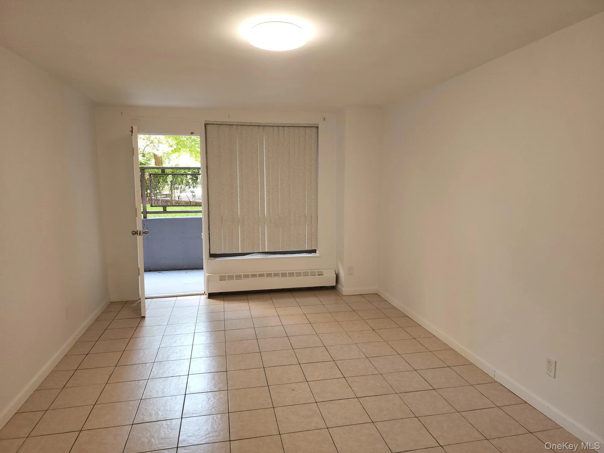 Unfurnished room with a baseboard radiator and light tile patterned floors Unfurnished room with a baseboard radiator and light tile patterned floors