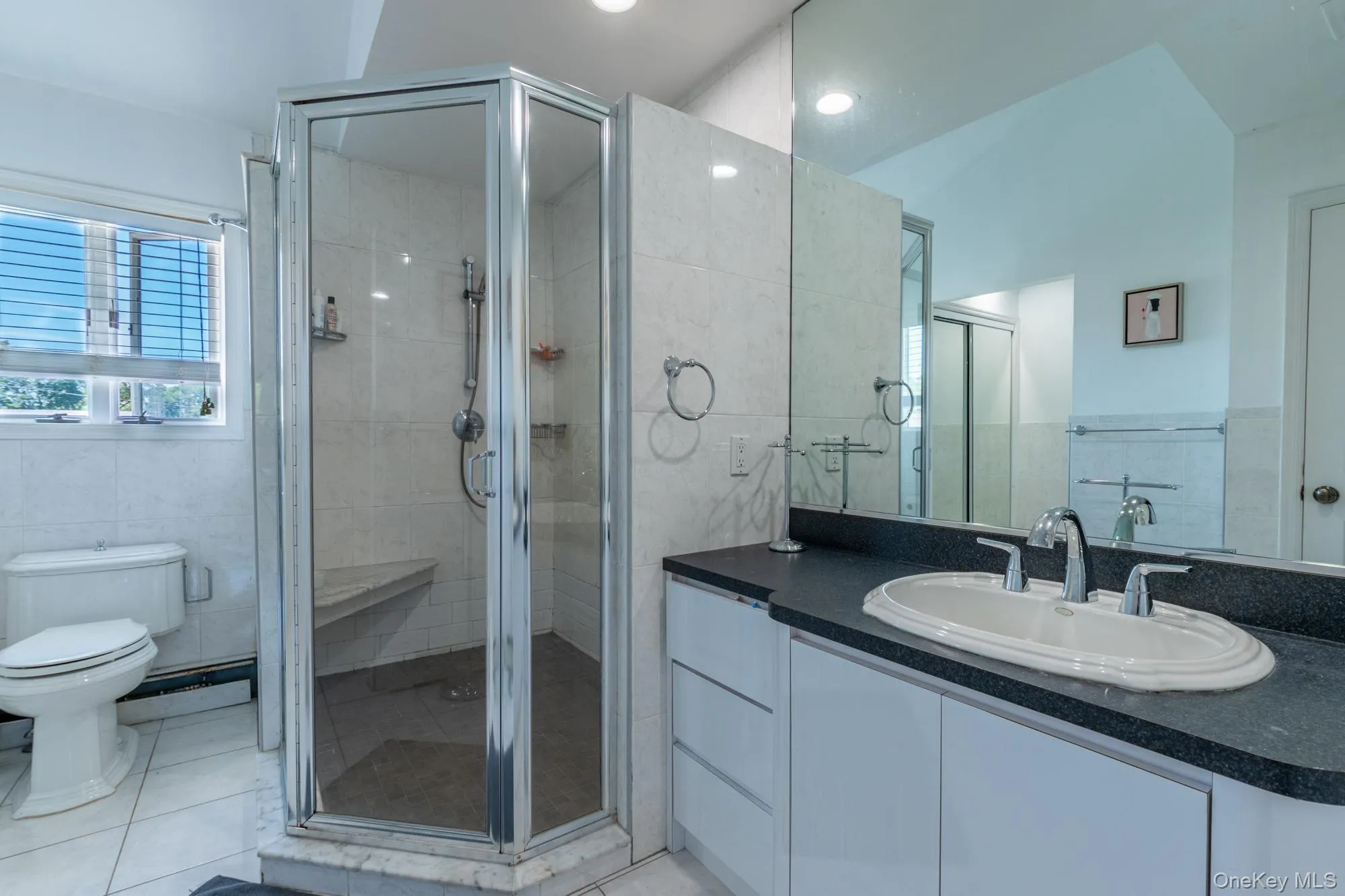 Bathroom with vanity, a stall shower, a baseboard heating unit, and light tile patterned floors Bathroom with vanity, a stall shower, a baseboard heating unit, and light tile patterned floors