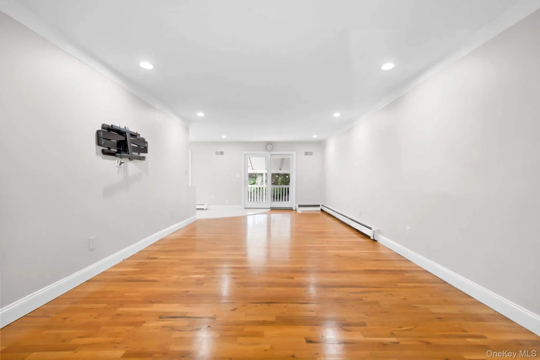 Spare room featuring ornamental molding, light wood-type flooring, recessed lighting, and a baseboard heating unit Spare room featuring ornamental molding, light wood-type flooring, recessed lighting, and a baseboard heating unit