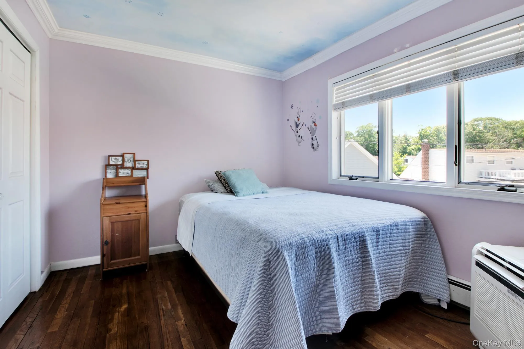Bedroom with dark wood finished floors, ornamental molding, and baseboard heating Bedroom with dark wood finished floors, ornamental molding, and baseboard heating
