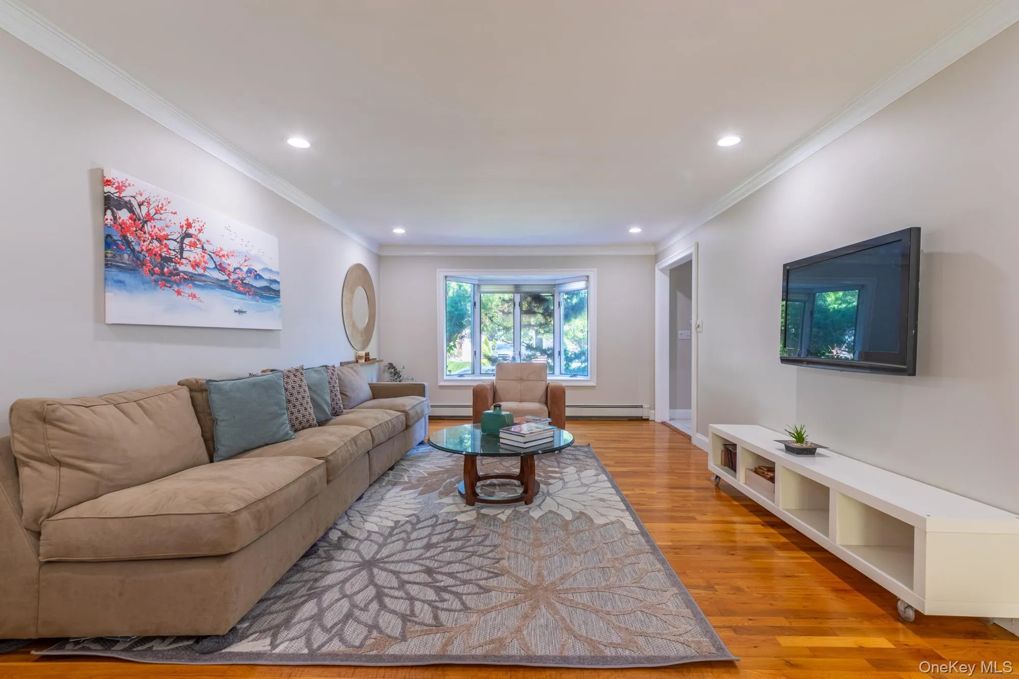 Living area featuring light wood-style floors, crown molding, recessed lighting, and baseboard heating Living area featuring light wood-style floors, crown molding, recessed lighting, and baseboard heating