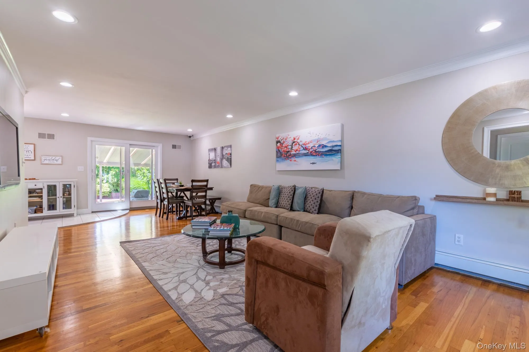 Living area with light wood-style flooring, recessed lighting, a baseboard heating unit, and crown molding Living area with light wood-style flooring, recessed lighting, a baseboard heating unit, and crown molding