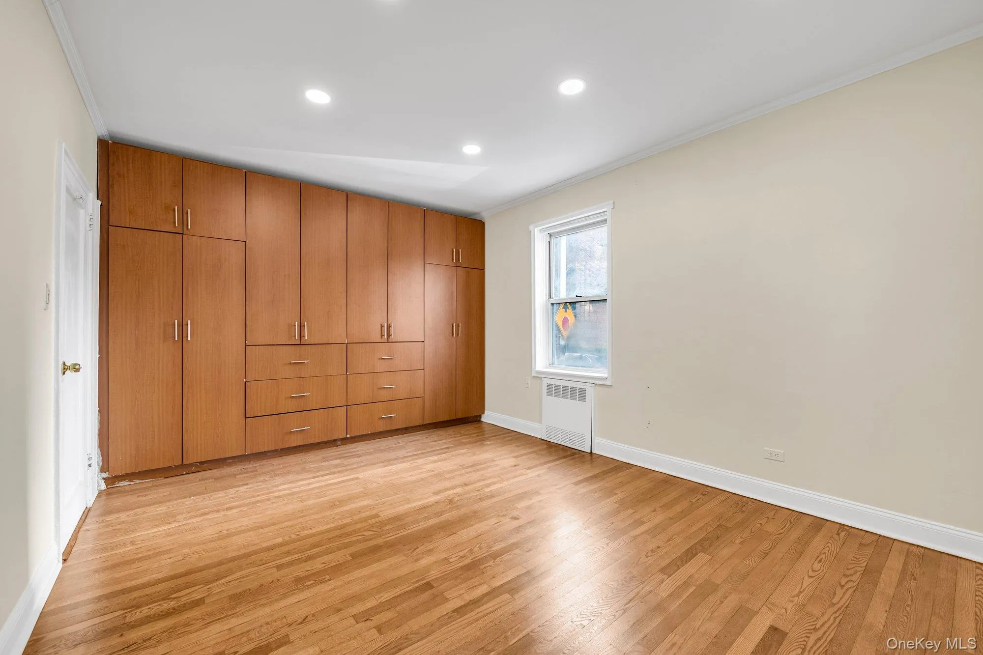 Unfurnished bedroom featuring ornamental molding, light wood-type flooring, a closet, radiator heating unit, and recessed lighting Unfurnished bedroom featuring ornamental molding, light wood-type flooring, a closet, radiator heating unit, and recessed lighting