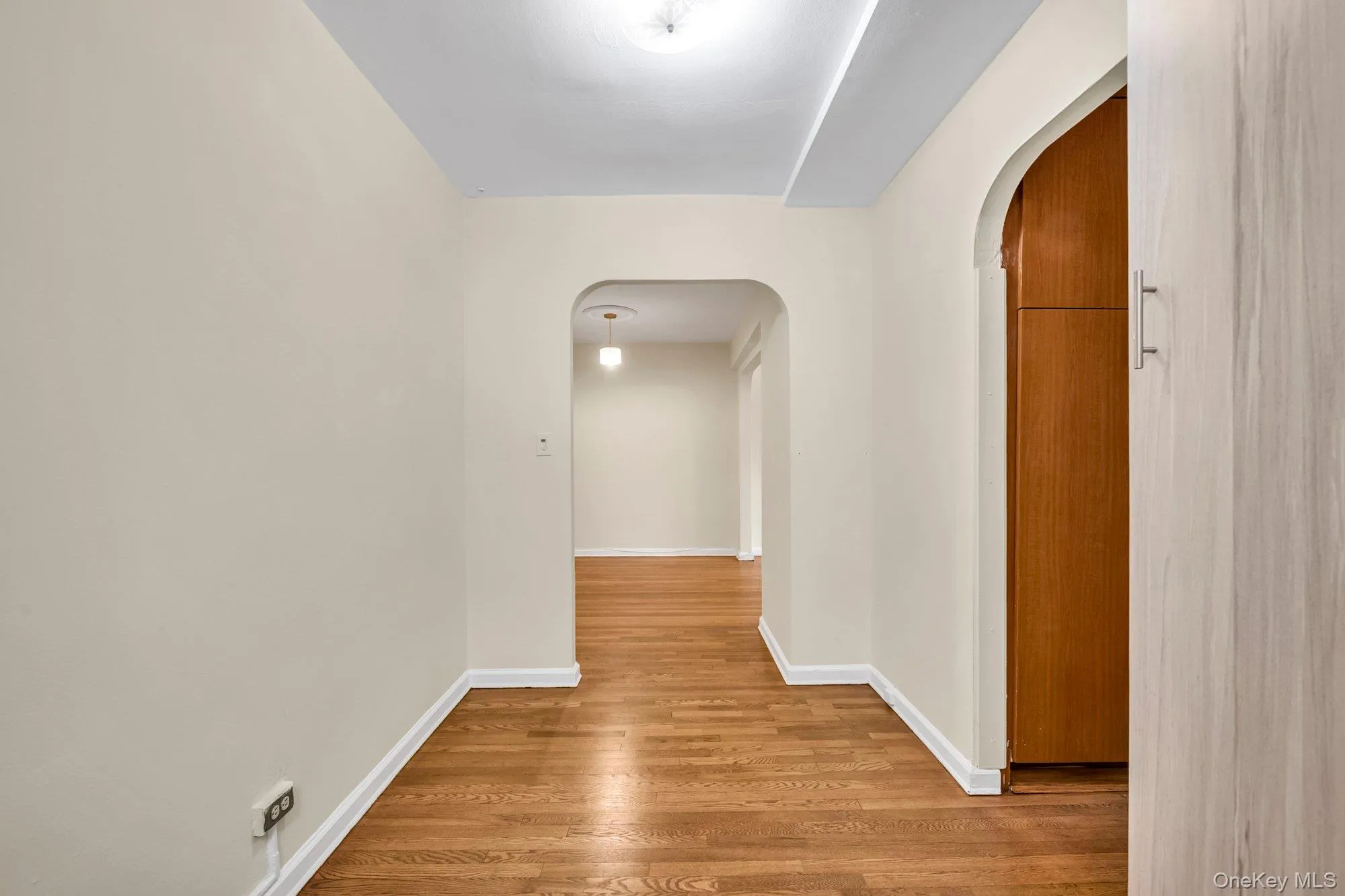 Hall featuring arched walkways and light wood-type flooring Hall featuring arched walkways and light wood-type flooring