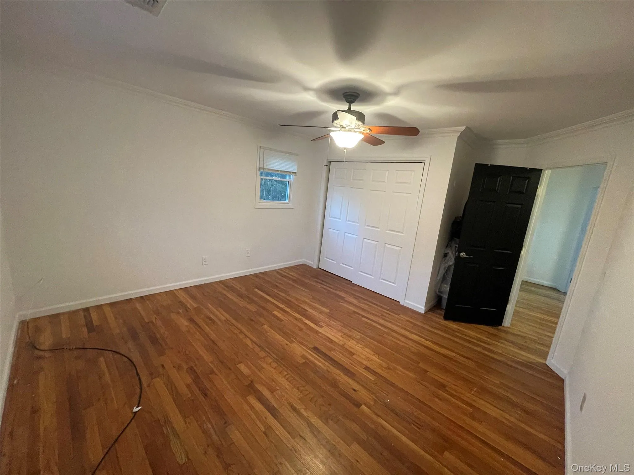 Unfurnished bedroom with dark wood-style floors, ceiling fan, crown molding, and a closet Unfurnished bedroom with dark wood-style floors, ceiling fan, crown molding, and a closet
