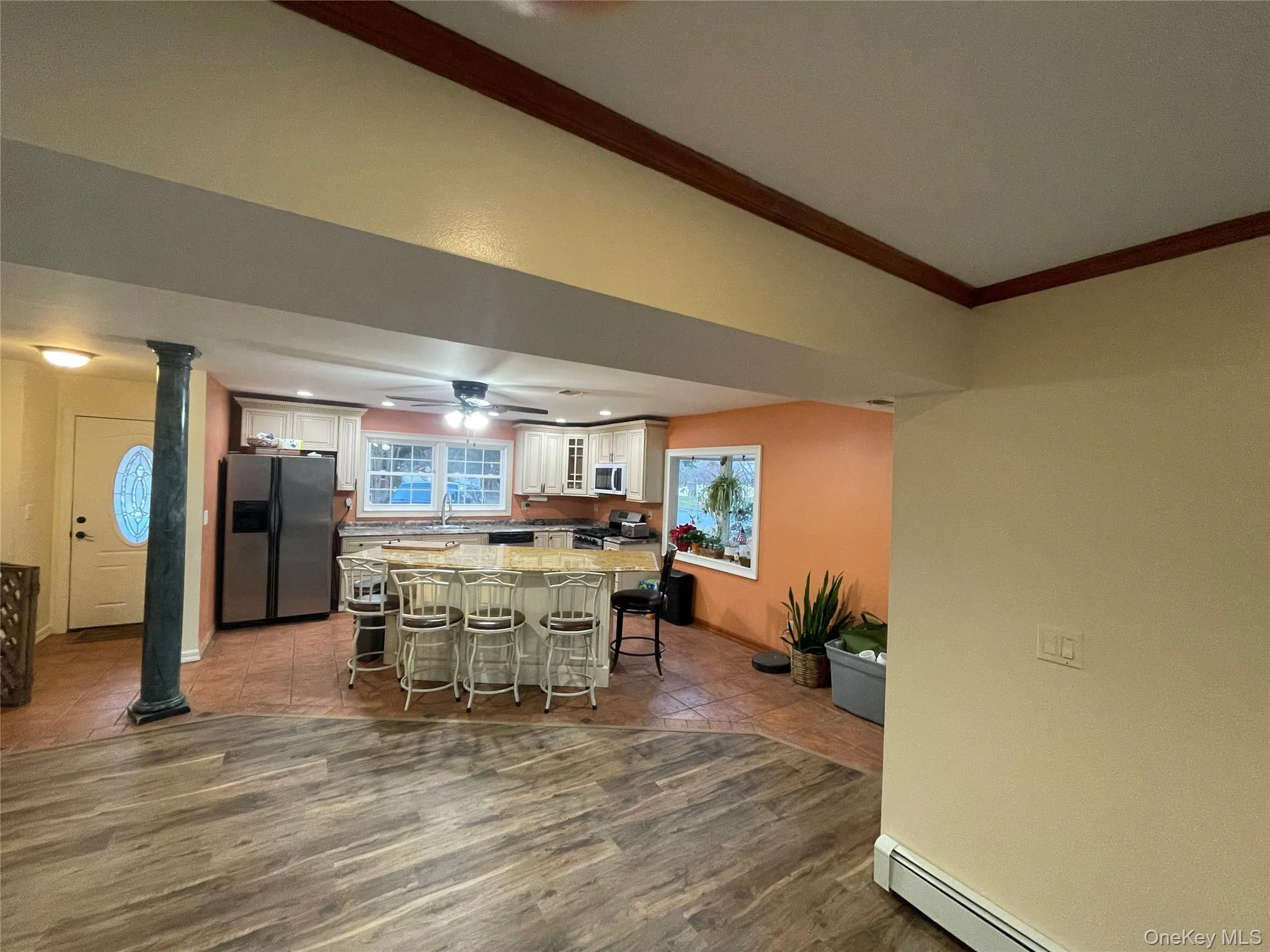 Kitchen with appliances with stainless steel finishes, a baseboard radiator, a breakfast bar, a center island, and a ceiling fan Kitchen with appliances with stainless steel finishes, a baseboard radiator, a breakfast bar, a center island, and a ceiling fan
