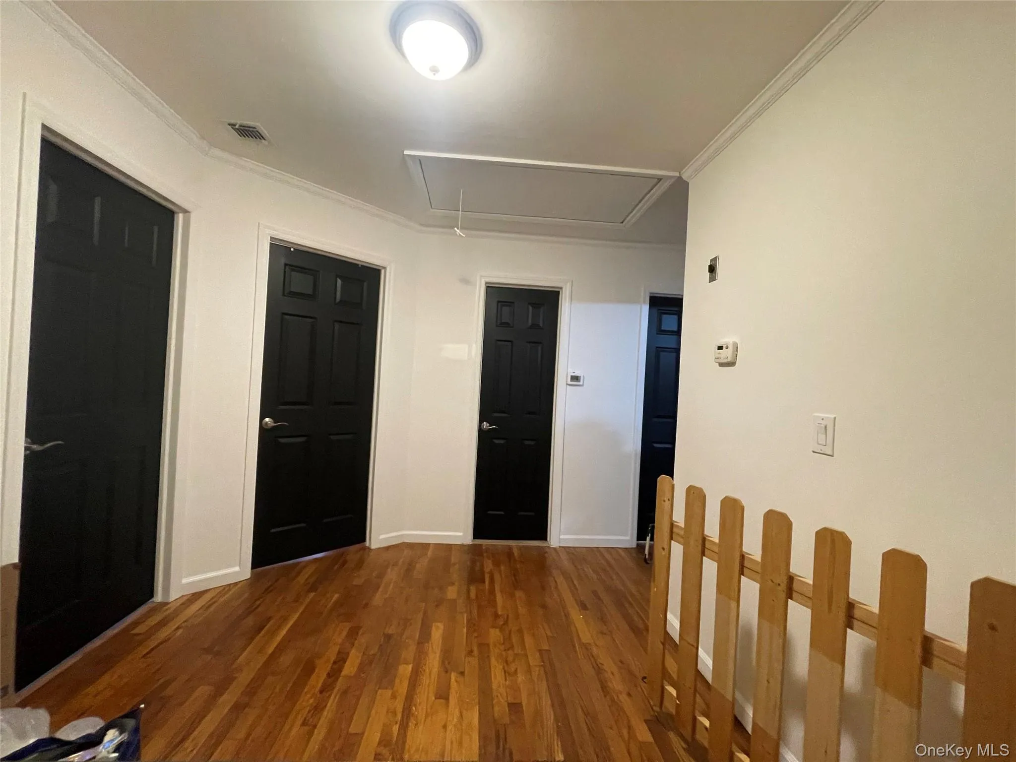 Hallway featuring attic access, dark wood finished floors, and crown molding Hallway featuring attic access, dark wood finished floors, and crown molding