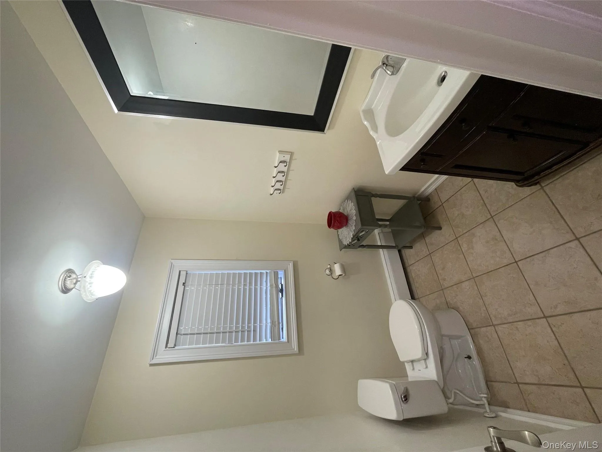 Bathroom featuring vanity, light tile patterned flooring, and a baseboard heating unit Bathroom featuring vanity, light tile patterned flooring, and a baseboard heating unit