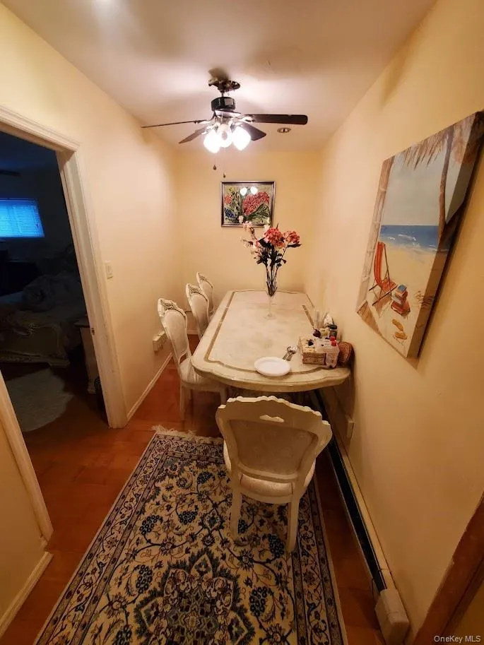 Dining area featuring wood finished floors, a ceiling fan, and baseboard heating Dining area featuring wood finished floors, a ceiling fan, and baseboard heating