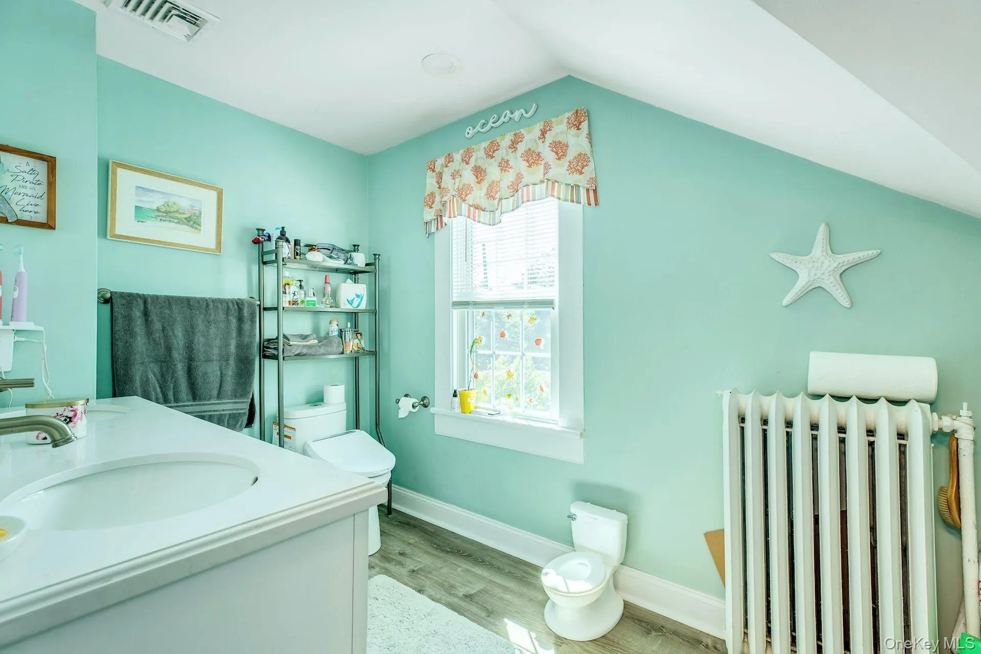 Full bath featuring radiator heating unit, double vanity, and wood finished floors Full bath featuring radiator heating unit, double vanity, and wood finished floors