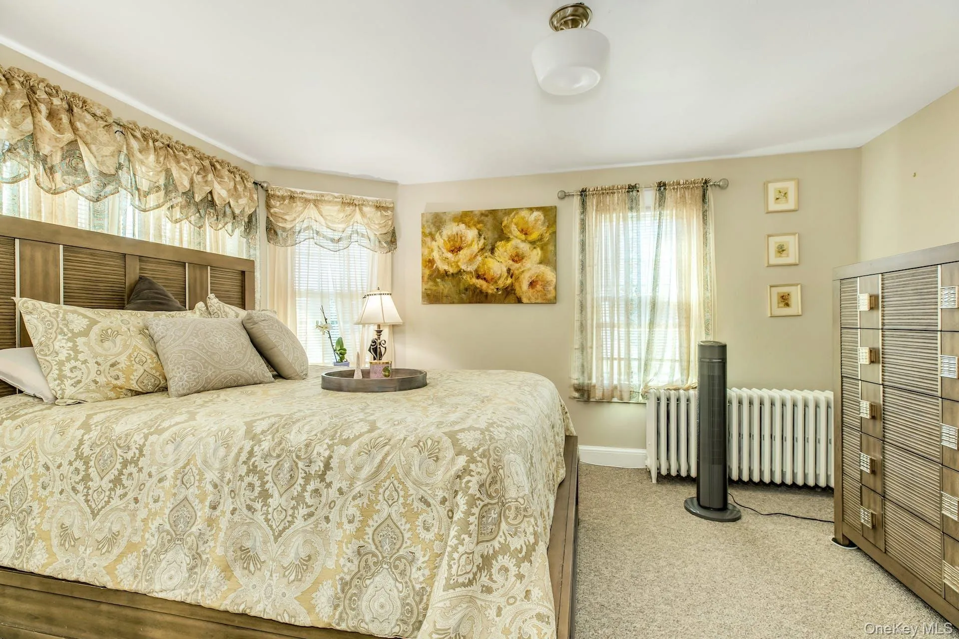 Bedroom with radiator heating unit, carpet floors, and multiple windows Bedroom with radiator heating unit, carpet floors, and multiple windows