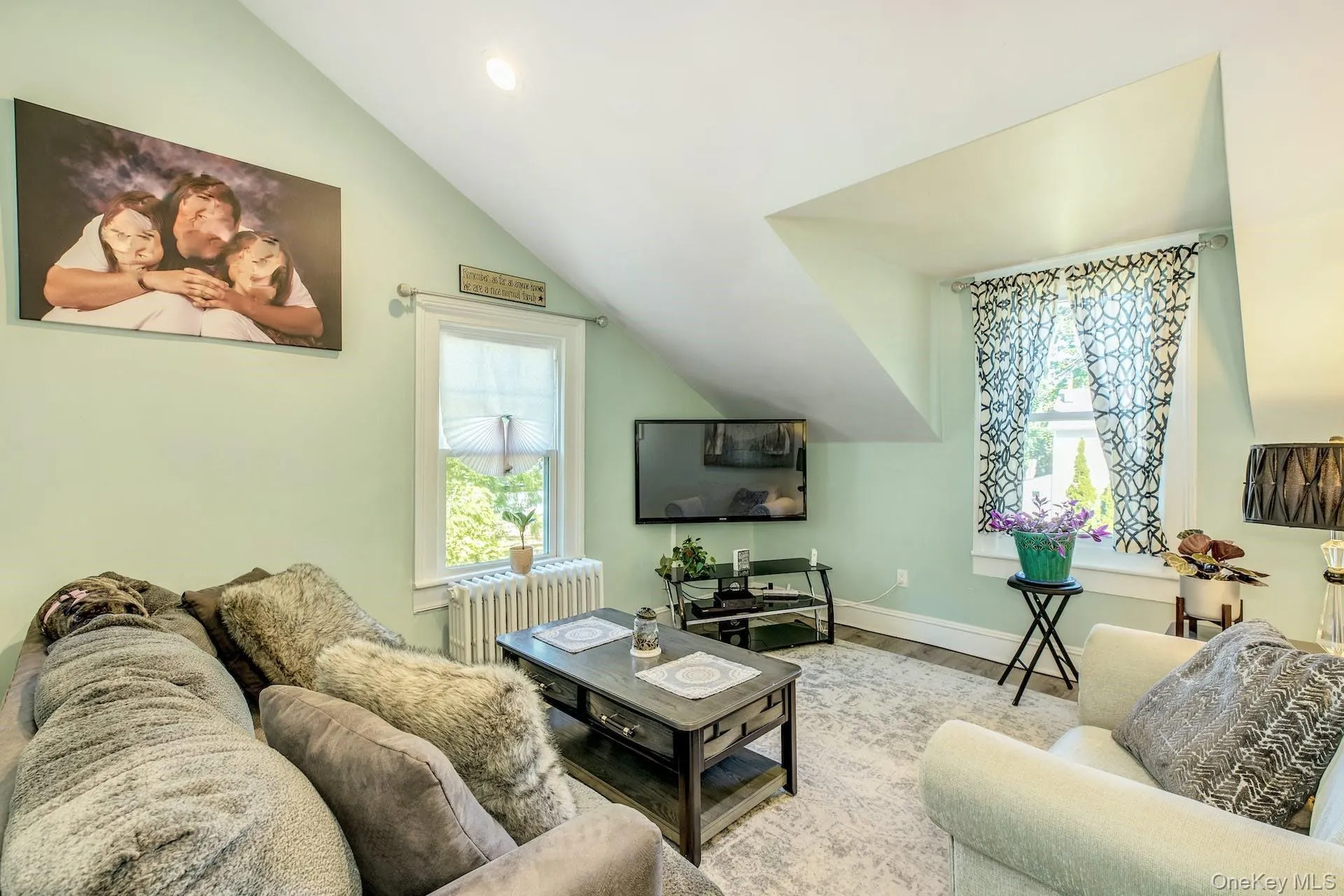 Living area featuring lofted ceiling, radiator heating unit, wood finished floors, and recessed lighting Living area featuring lofted ceiling, radiator heating unit, wood finished floors, and recessed lighting