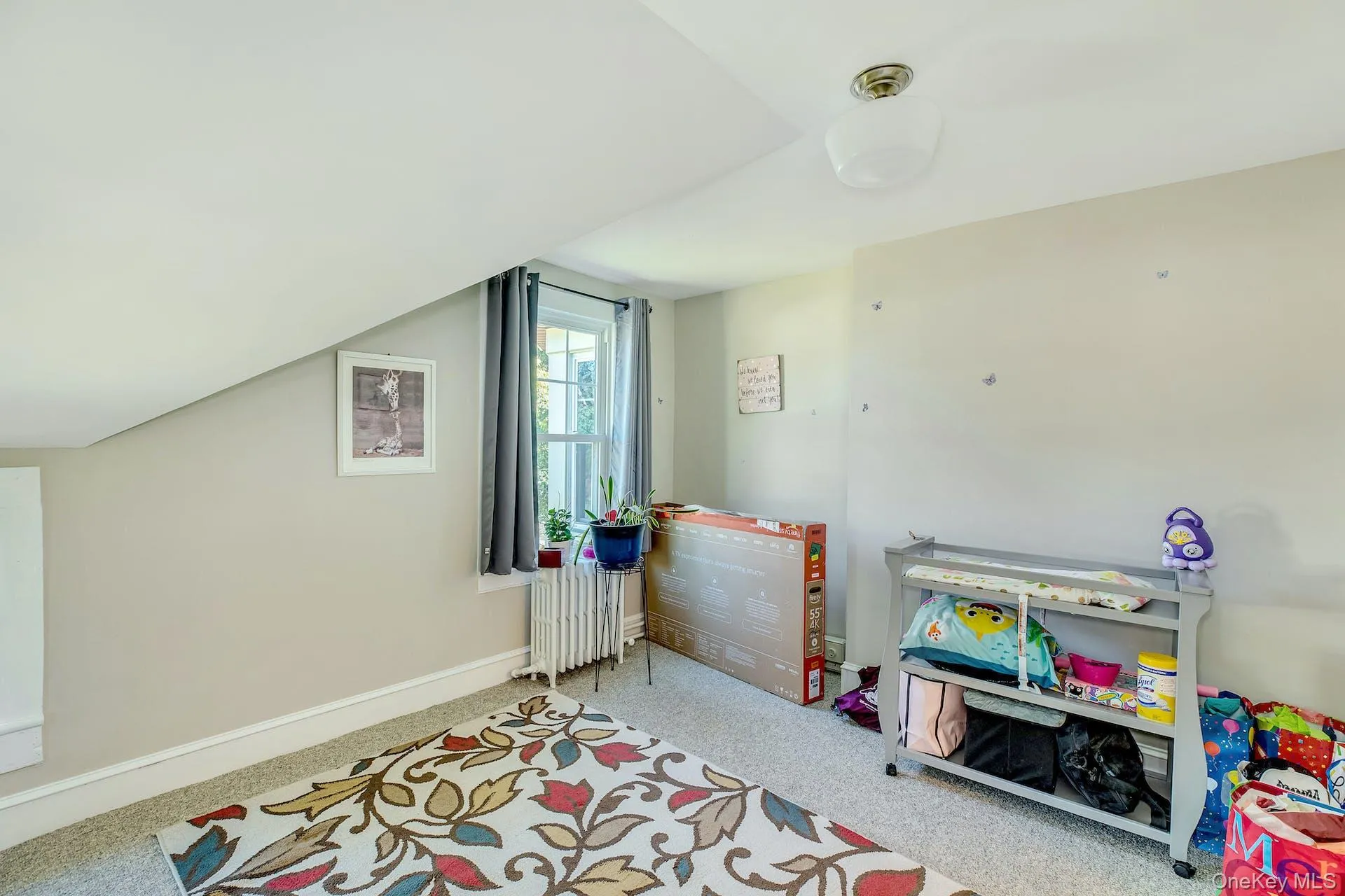 Playroom featuring radiator heating unit, carpet flooring, and vaulted ceiling Playroom featuring radiator heating unit, carpet flooring, and vaulted ceiling