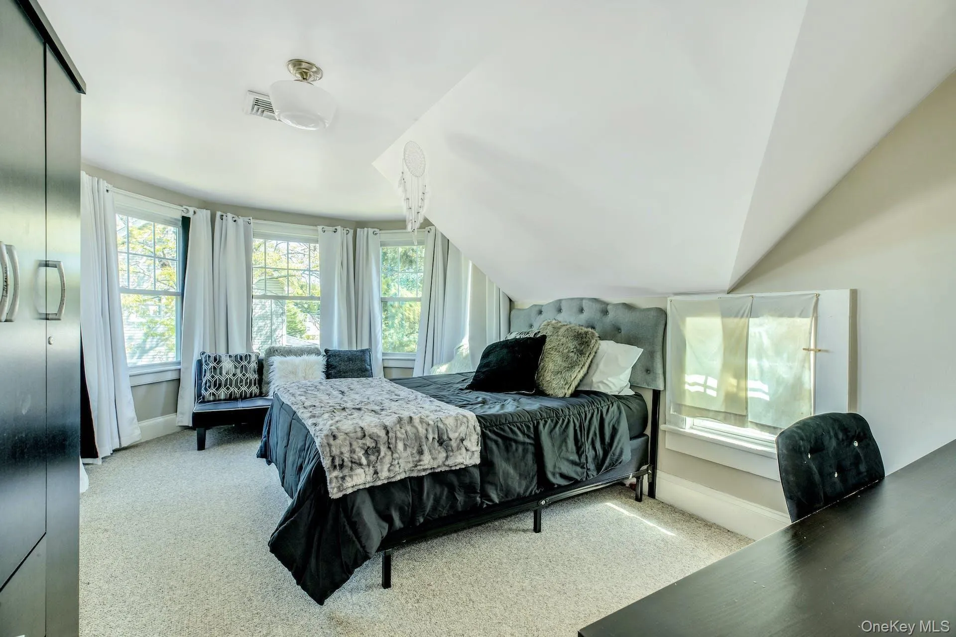 Bedroom featuring multiple windows, lofted ceiling, and light colored carpet Bedroom featuring multiple windows, lofted ceiling, and light colored carpet