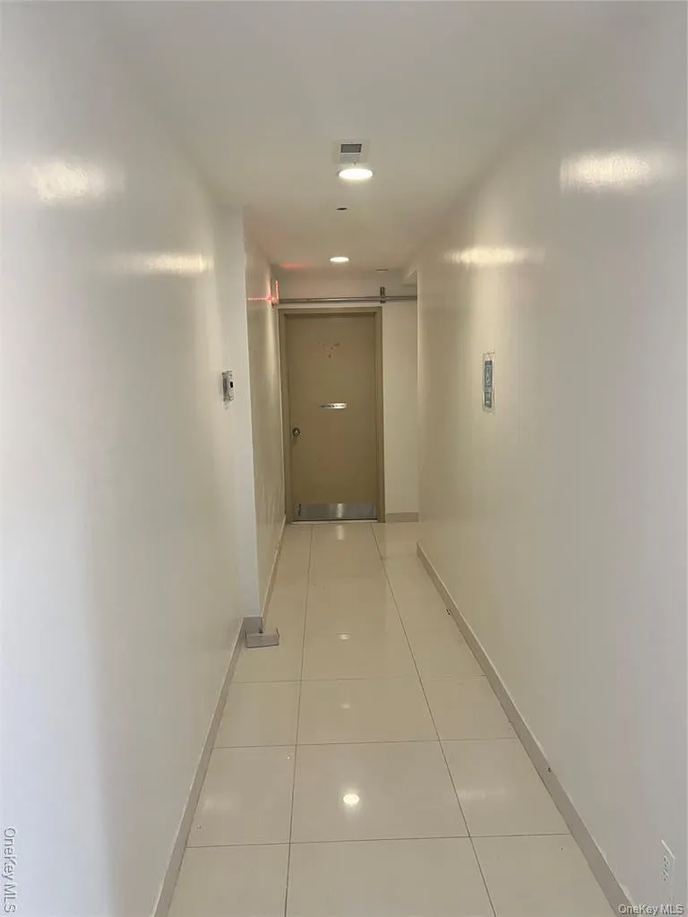 Corridor with a barn door, light tile patterned flooring, and recessed lighting Corridor with a barn door, light tile patterned flooring, and recessed lighting