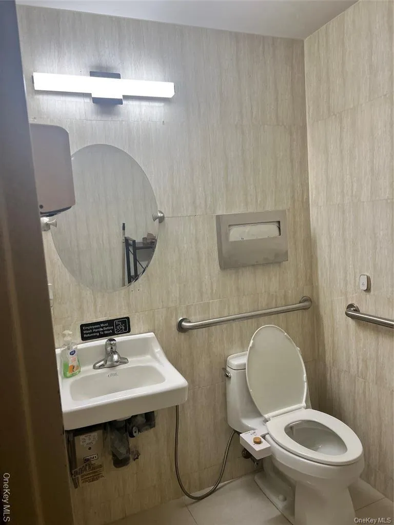 Half bathroom featuring tile patterned floors and tile walls Half bathroom featuring tile patterned floors and tile walls