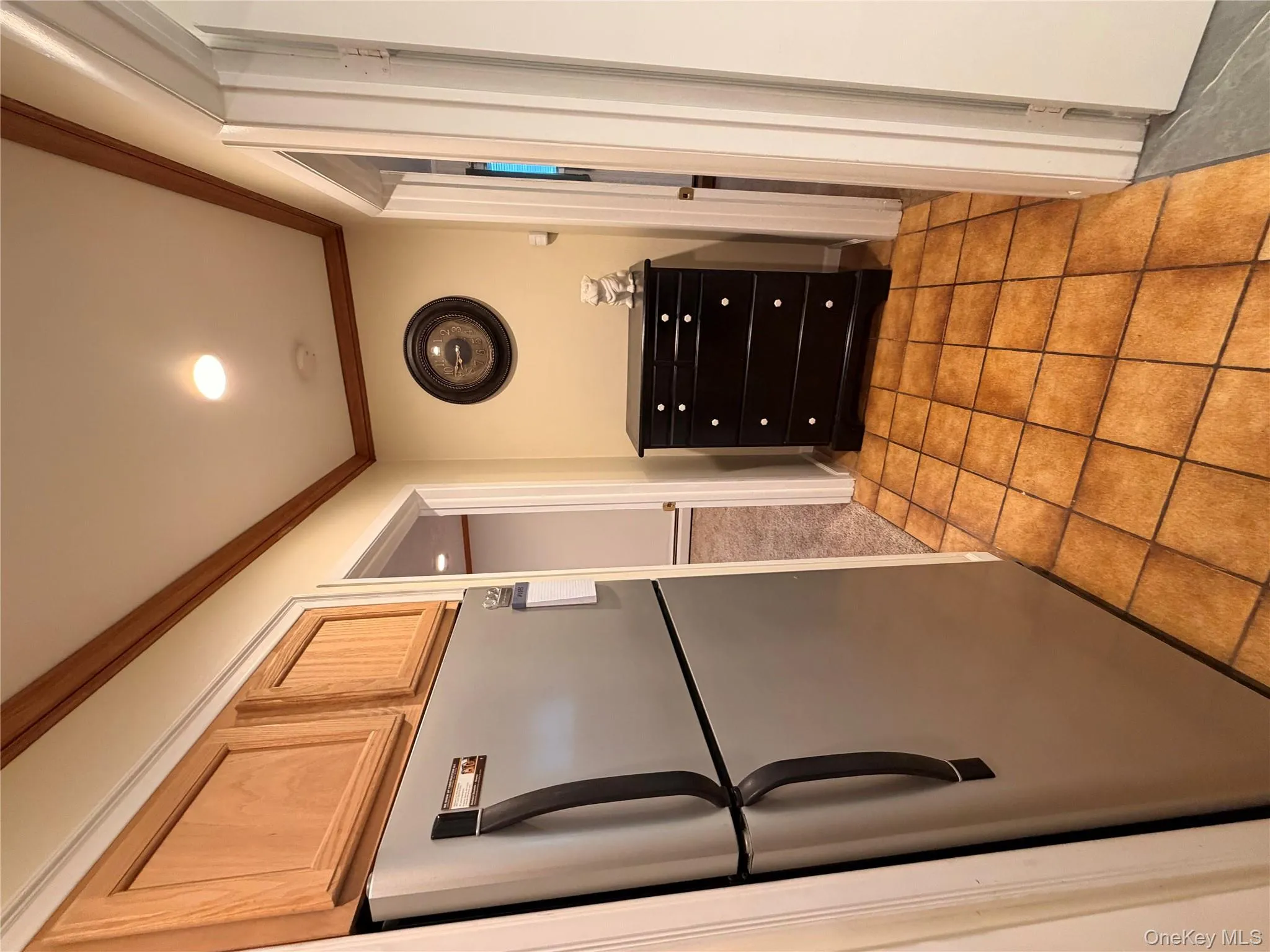 Kitchen featuring stainless steel refrigerator, ornamental molding, light tile patterned floors, and light brown cabinetry Kitchen featuring stainless steel refrigerator, ornamental molding, light tile patterned floors, and light brown cabinetry