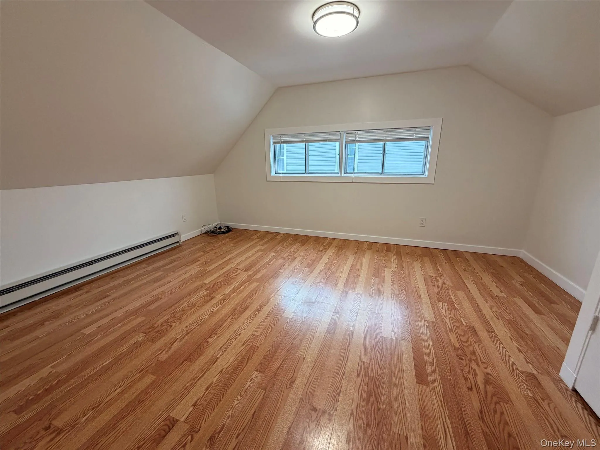 Bonus room featuring baseboard heating, lofted ceiling, and light wood-style floors Bonus room featuring baseboard heating, lofted ceiling, and light wood-style floors