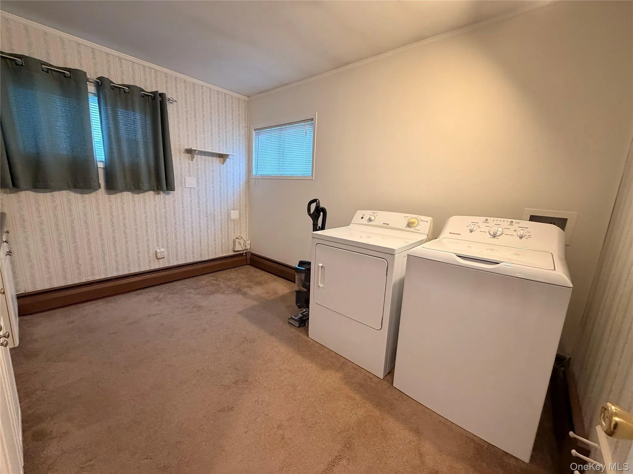 Laundry room with ornamental molding, light colored carpet, a baseboard heating unit, and separate washer and dryer Laundry room with ornamental molding, light colored carpet, a baseboard heating unit, and separate washer and dryer