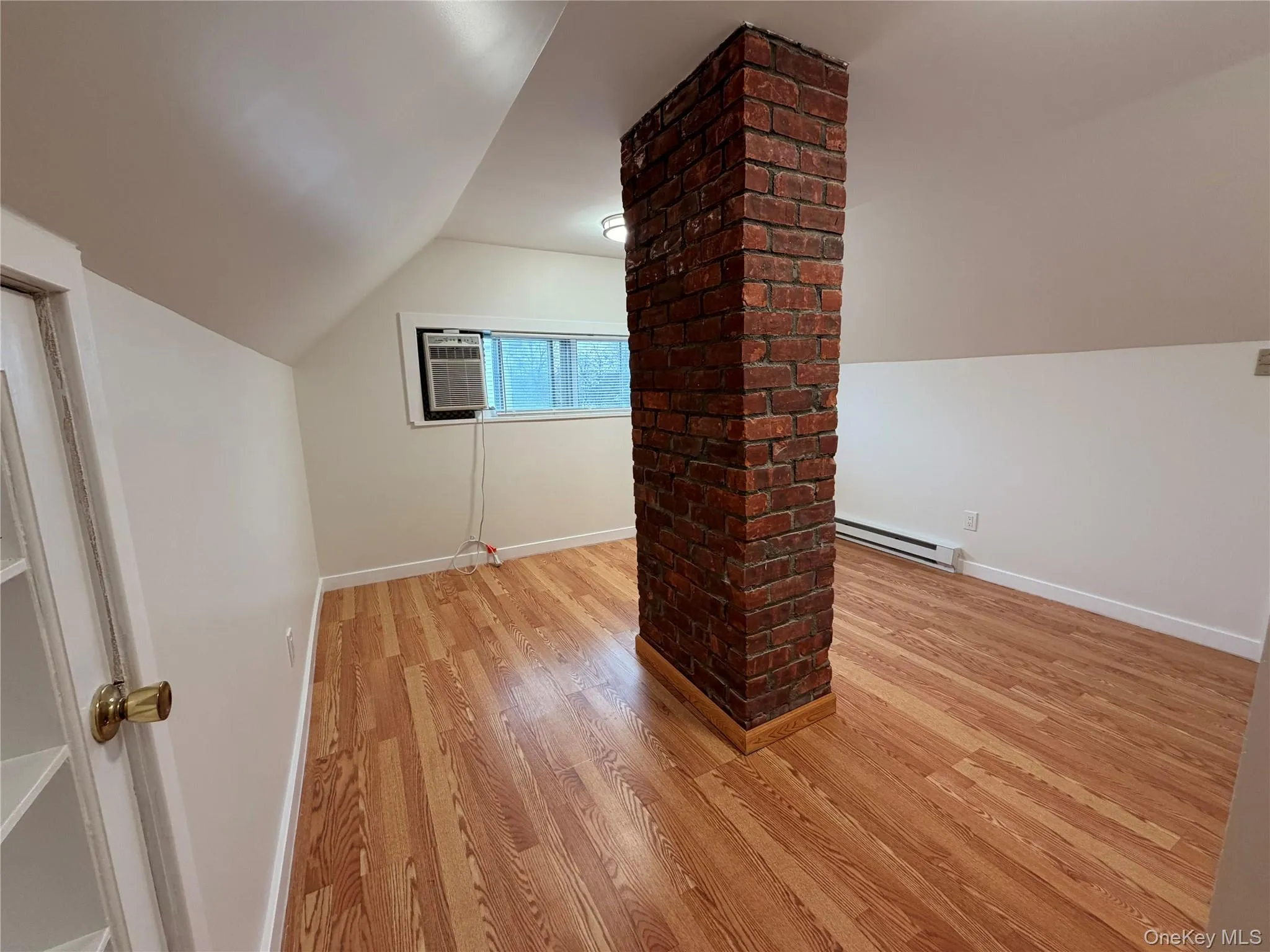 Additional living space with lofted ceiling, light wood-style flooring, and a baseboard heating unit Additional living space with lofted ceiling, light wood-style flooring, and a baseboard heating unit