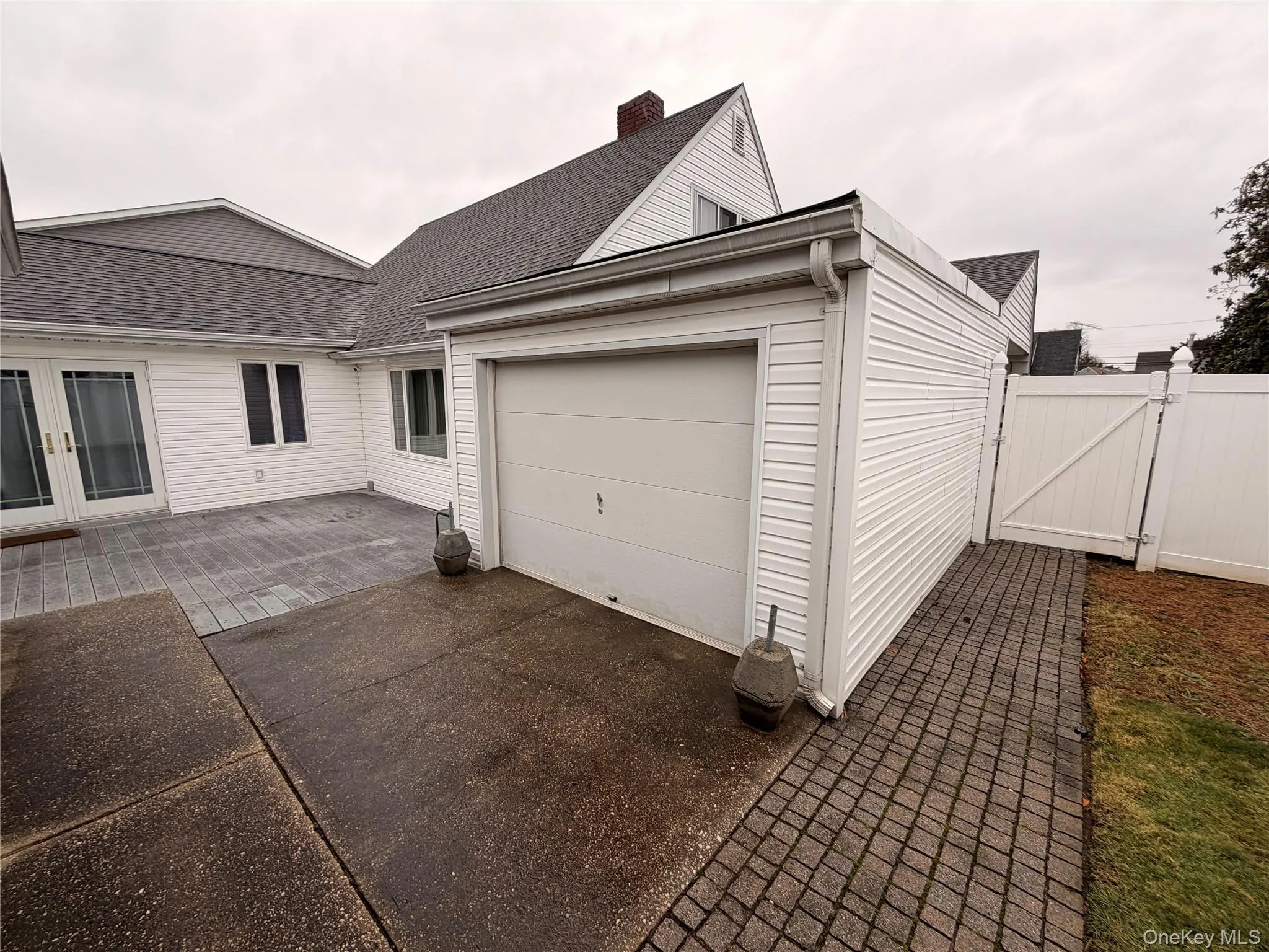 View of home's exterior featuring roof with shingles, a gate, driveway, a garage, and french doors View of home's exterior featuring roof with shingles, a gate, driveway, a garage, and french doors