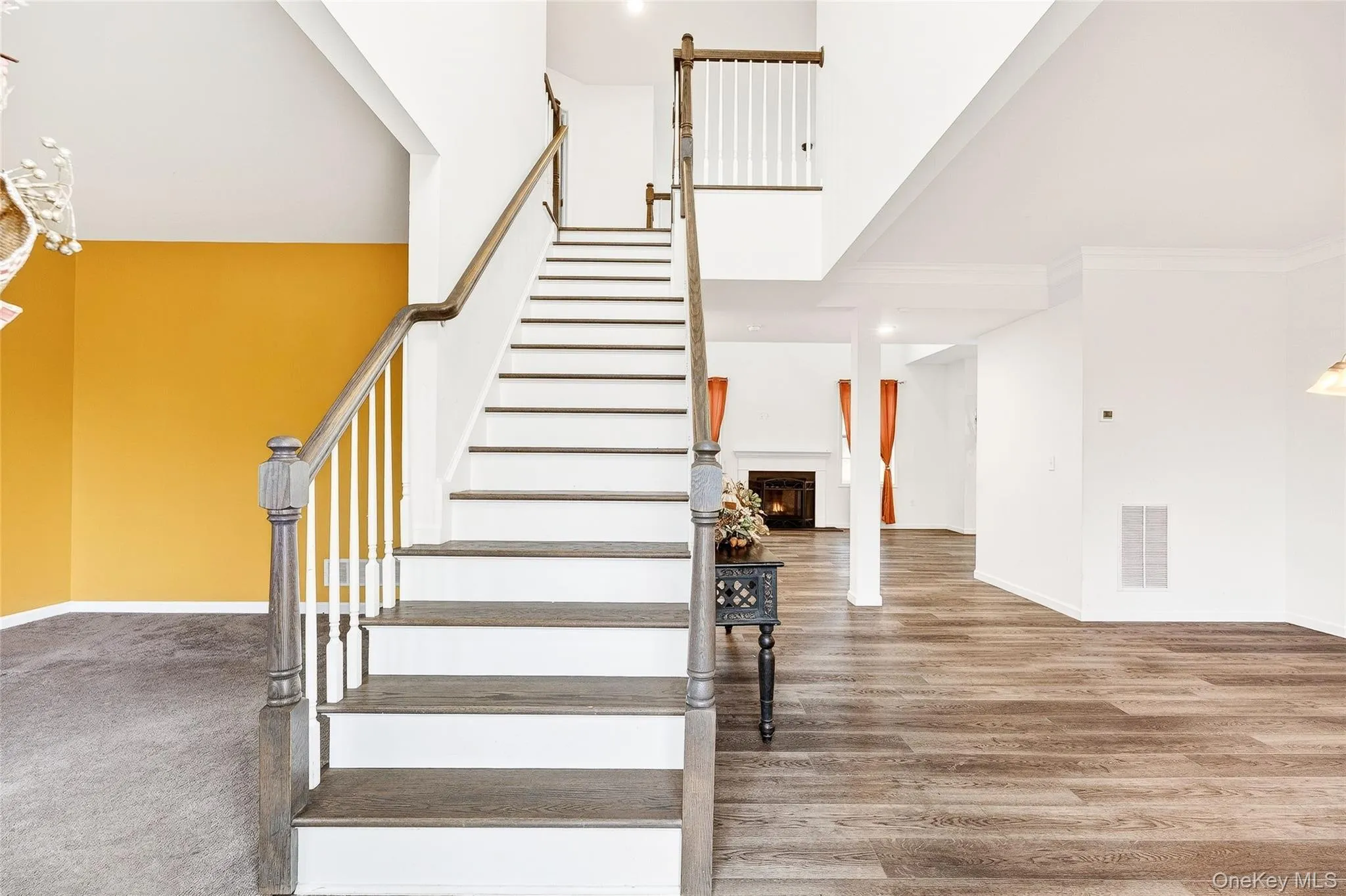 Staircase with a towering ceiling, a lit fireplace, wood finished floors, and a chandelier Staircase with a towering ceiling, a lit fireplace, wood finished floors, and a chandelier