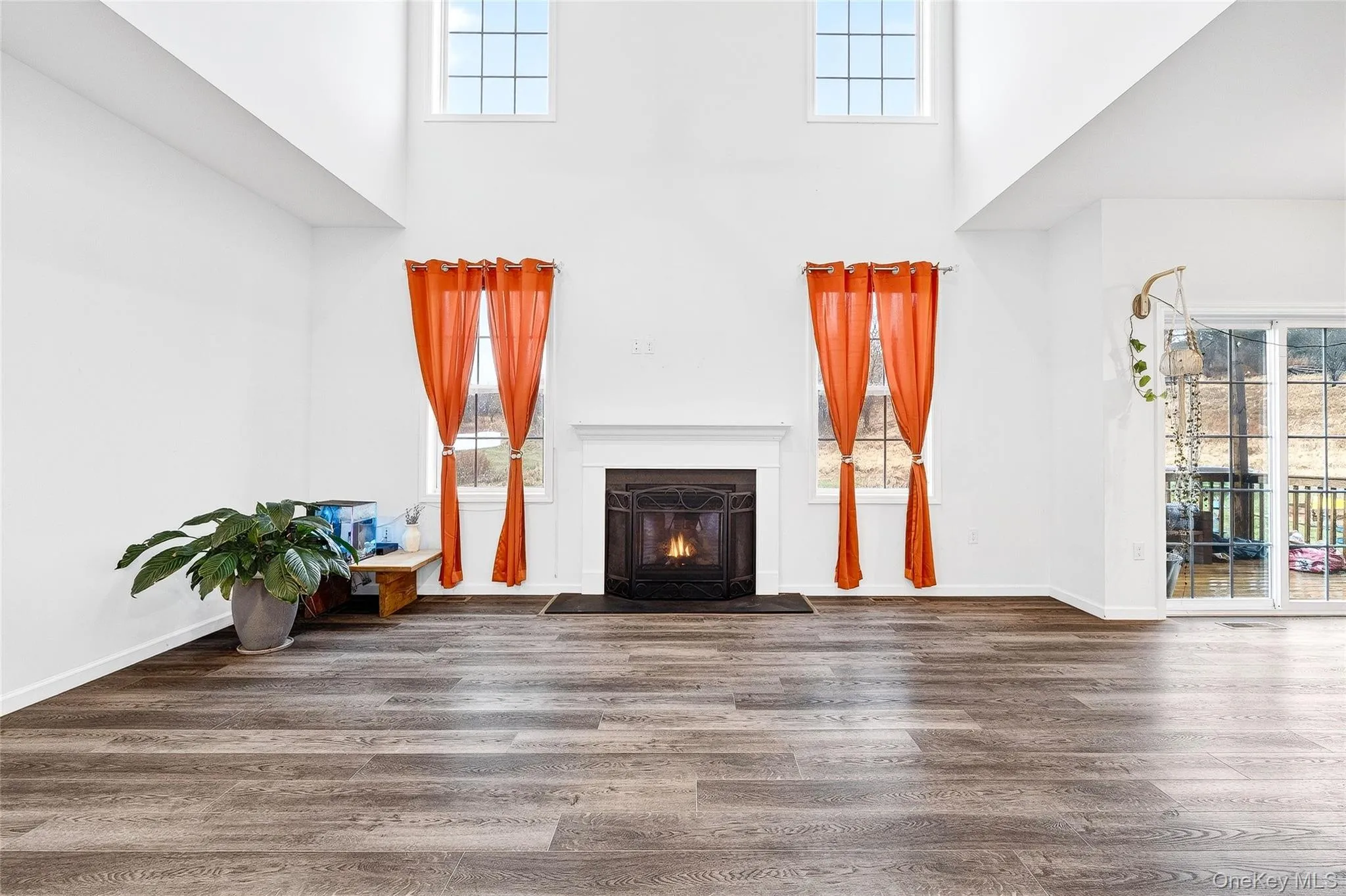 Unfurnished living room with a high ceiling, a fireplace with flush hearth, and wood finished floors Unfurnished living room with a high ceiling, a fireplace with flush hearth, and wood finished floors