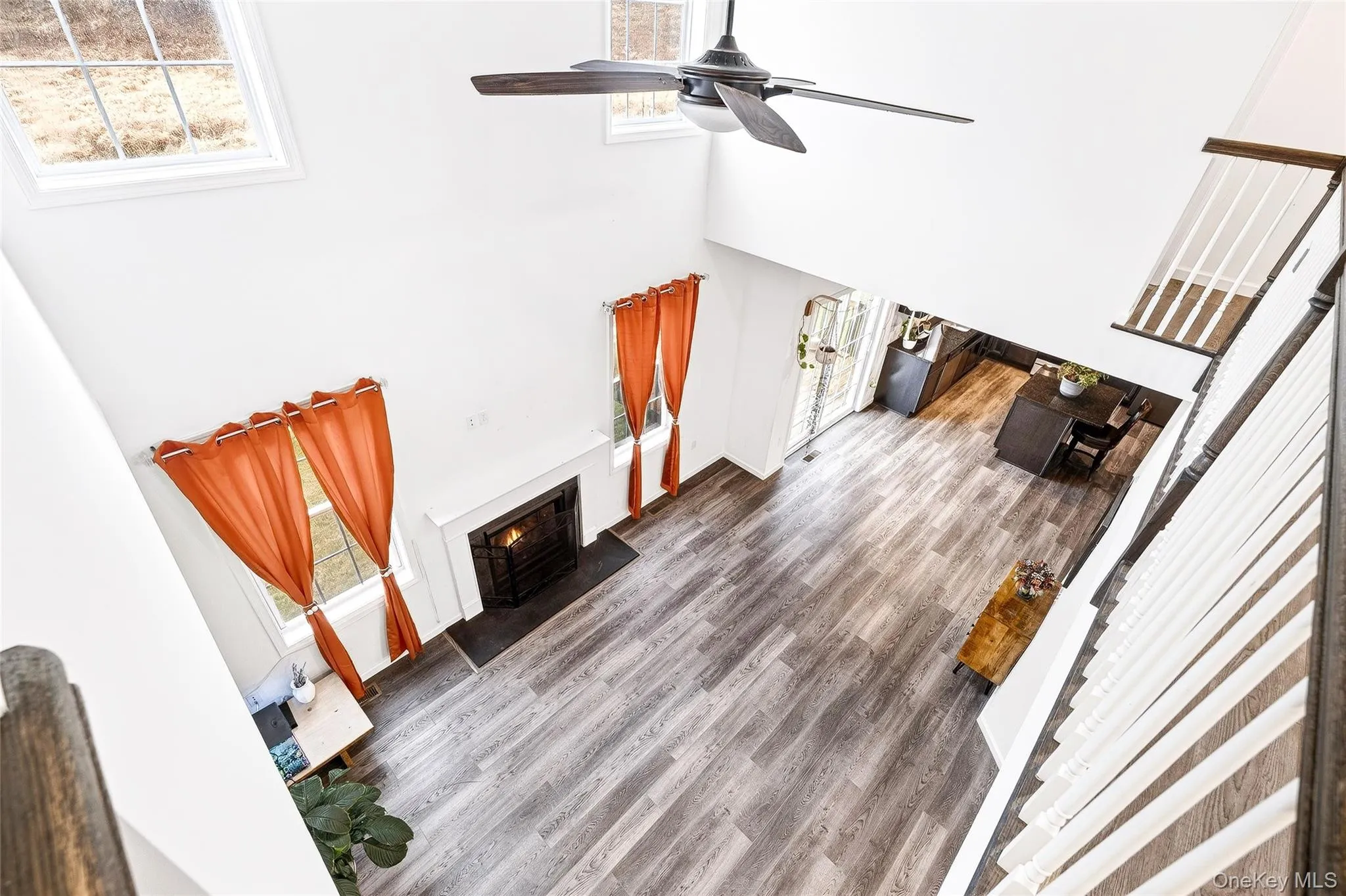 Unfurnished living room featuring a lit fireplace, a towering ceiling, wood finished floors, and ceiling fan Unfurnished living room featuring a lit fireplace, a towering ceiling, wood finished floors, and ceiling fan