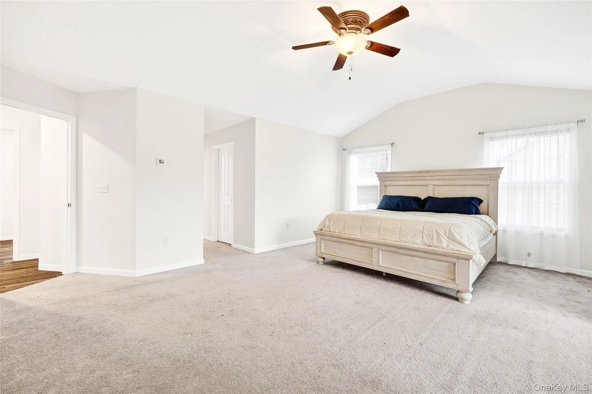 Carpeted bedroom with vaulted ceiling and a ceiling fan Carpeted bedroom with vaulted ceiling and a ceiling fan
