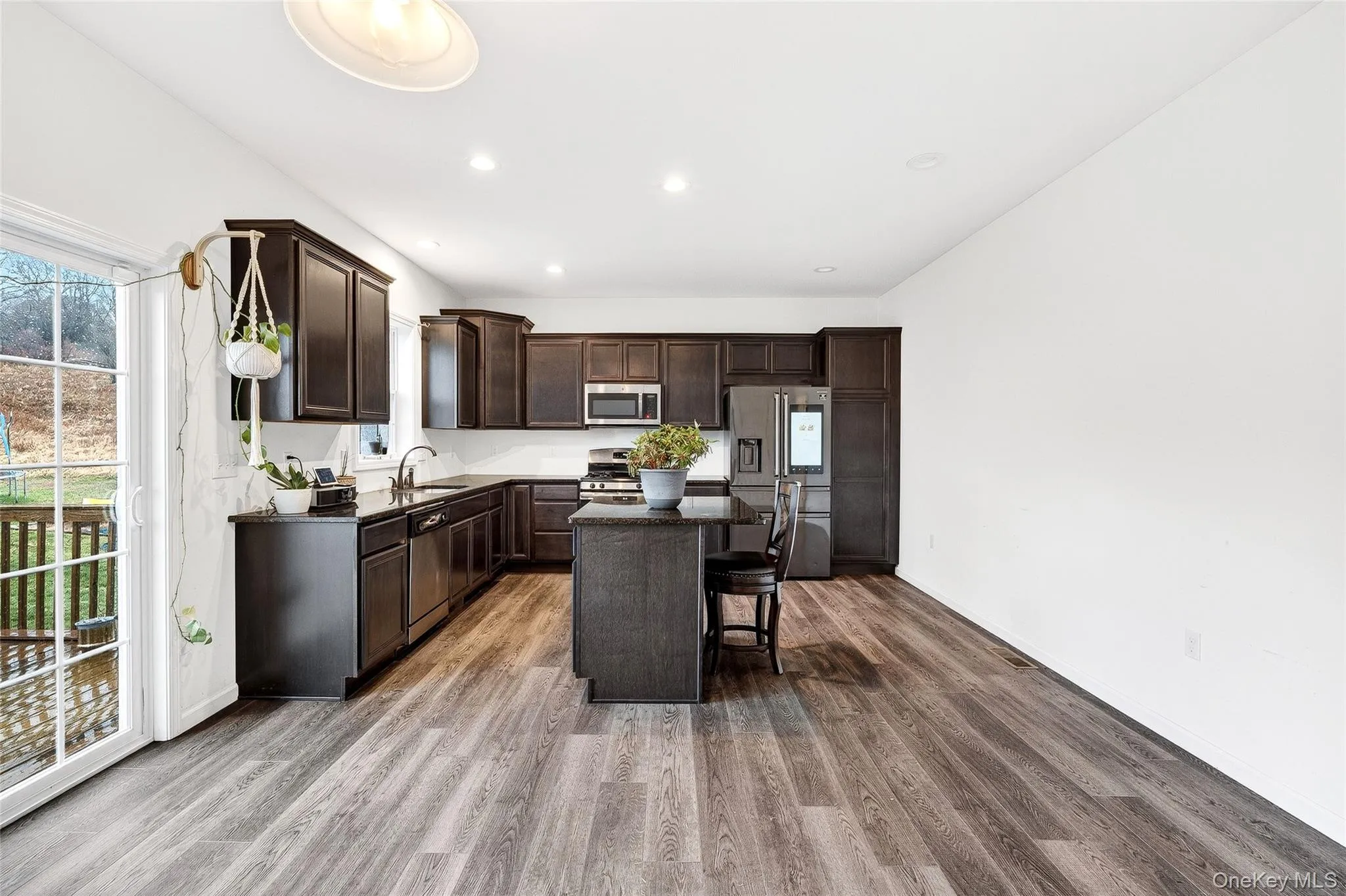 Kitchen with dark brown cabinetry, a center island, a breakfast bar area, appliances with stainless steel finishes, and dark wood finished floors Kitchen with dark brown cabinetry, a center island, a breakfast bar area, appliances with stainless steel finishes, and dark wood finished floors