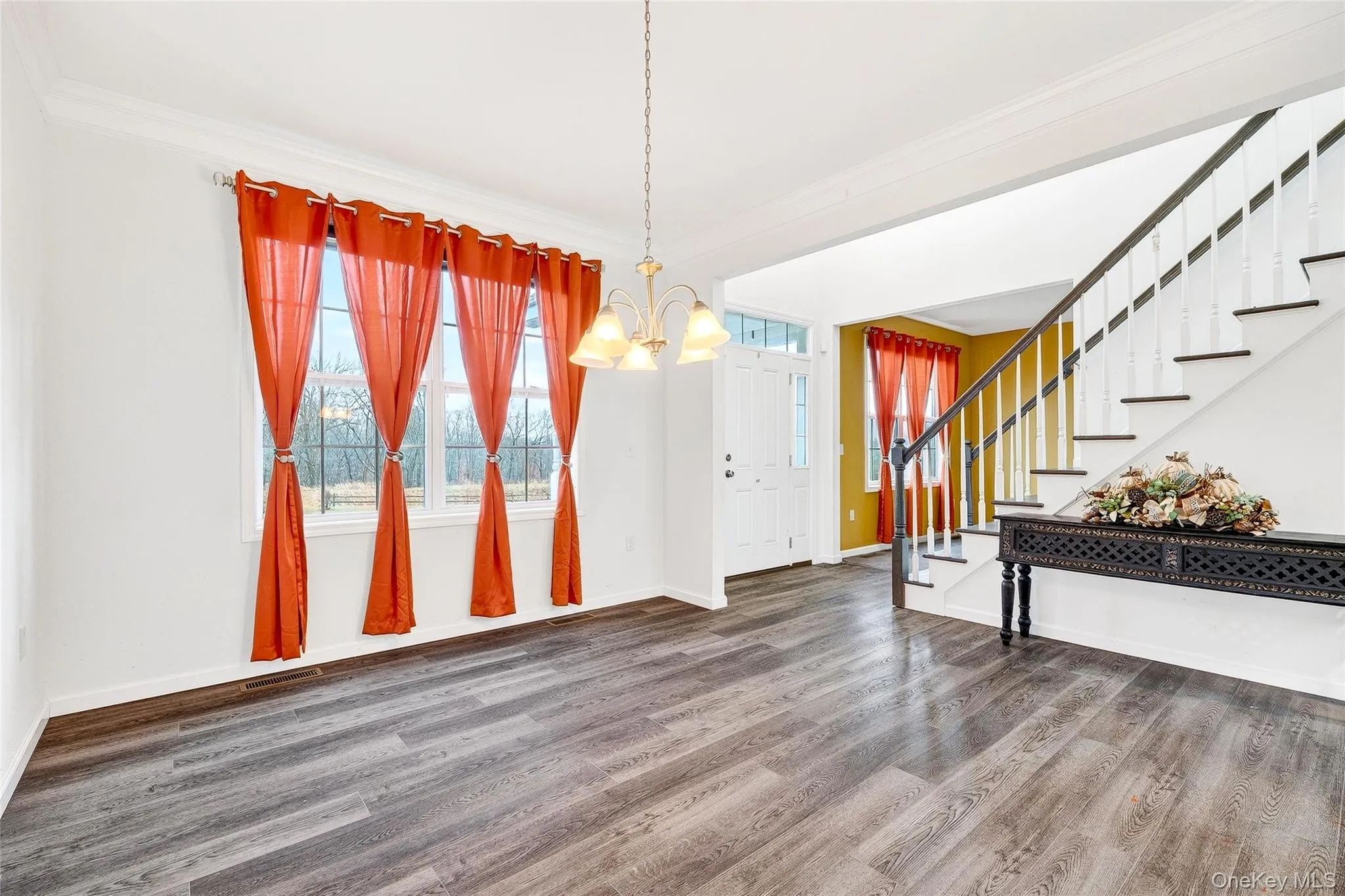 Foyer with ornamental molding, stairway, a chandelier, and wood finished floors Foyer with ornamental molding, stairway, a chandelier, and wood finished floors