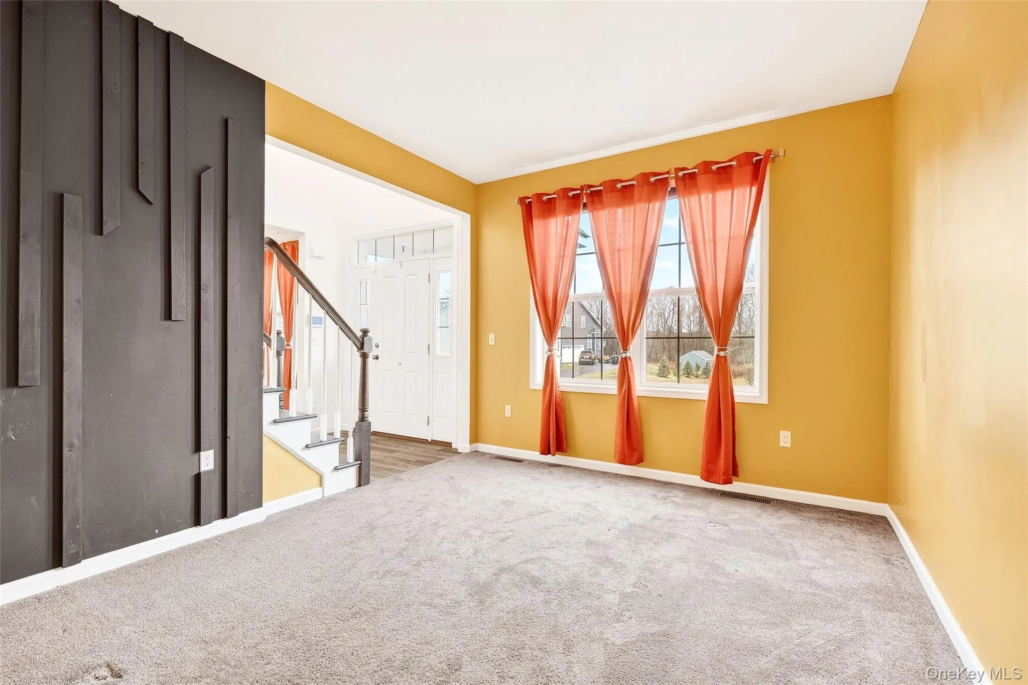 Carpeted spare room featuring baseboards and stairway Carpeted spare room featuring baseboards and stairway