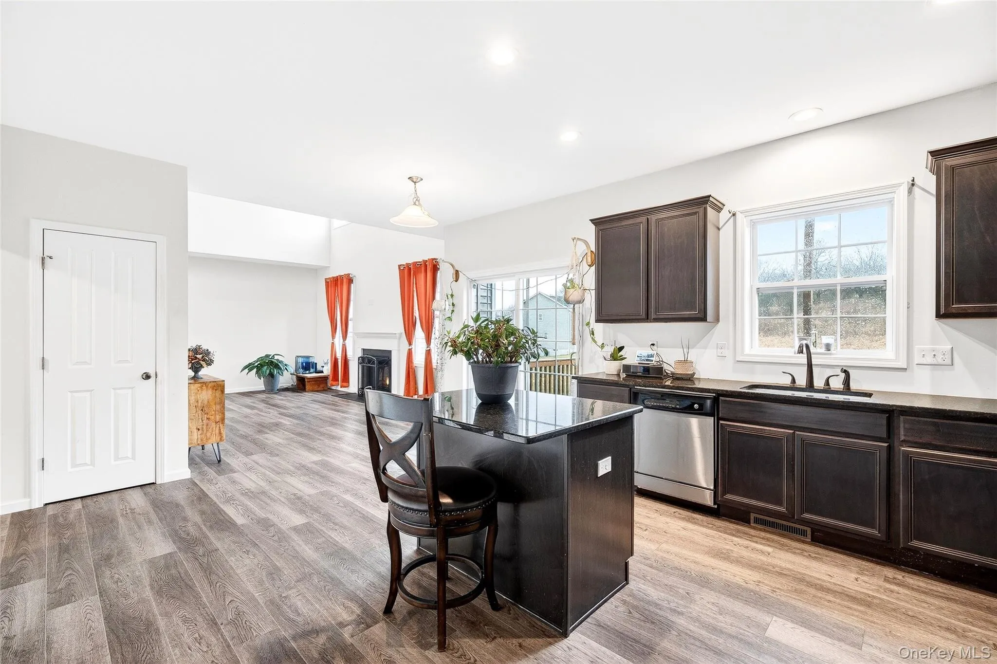 Kitchen featuring a kitchen bar, dark brown cabinets, a kitchen island, dishwasher, and light wood-type flooring Kitchen featuring a kitchen bar, dark brown cabinets, a kitchen island, dishwasher, and light wood-type flooring