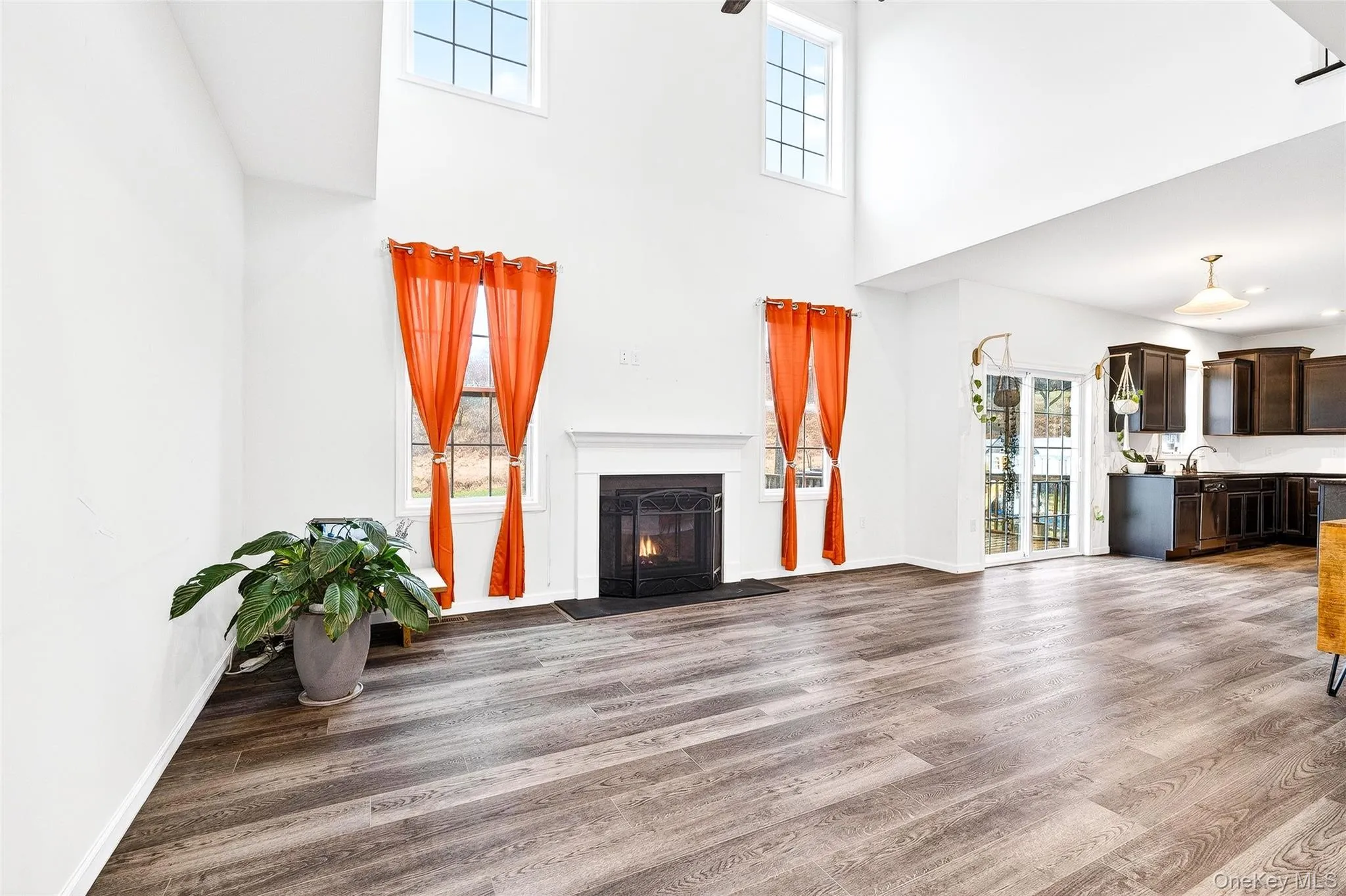 Unfurnished living room with dark wood-style flooring, a fireplace with flush hearth, and a high ceiling Unfurnished living room with dark wood-style flooring, a fireplace with flush hearth, and a high ceiling