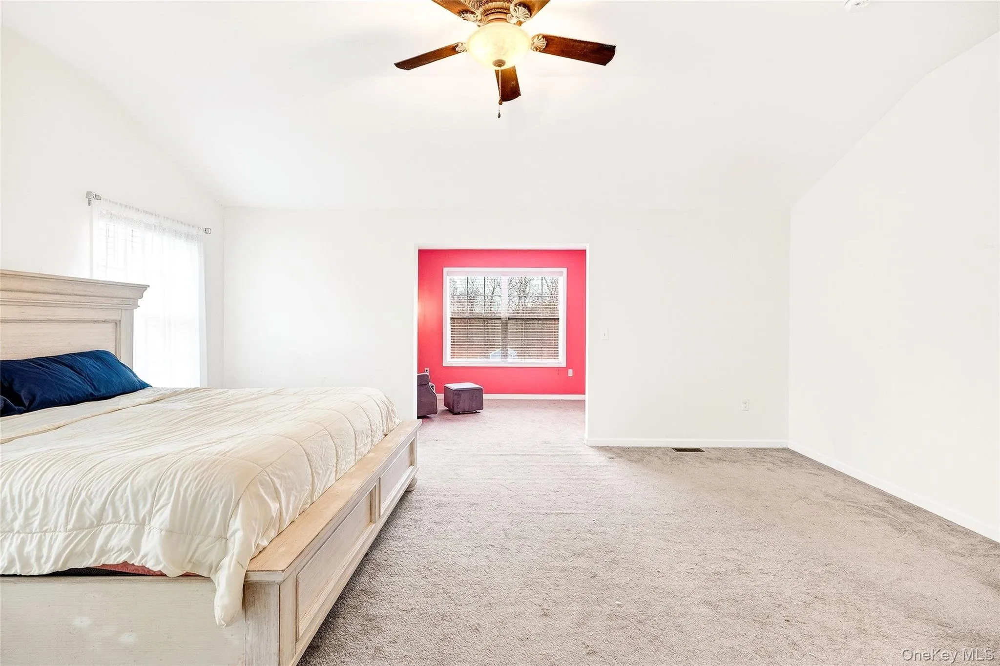 Bedroom featuring vaulted ceiling, light carpet, and a ceiling fan Bedroom featuring vaulted ceiling, light carpet, and a ceiling fan