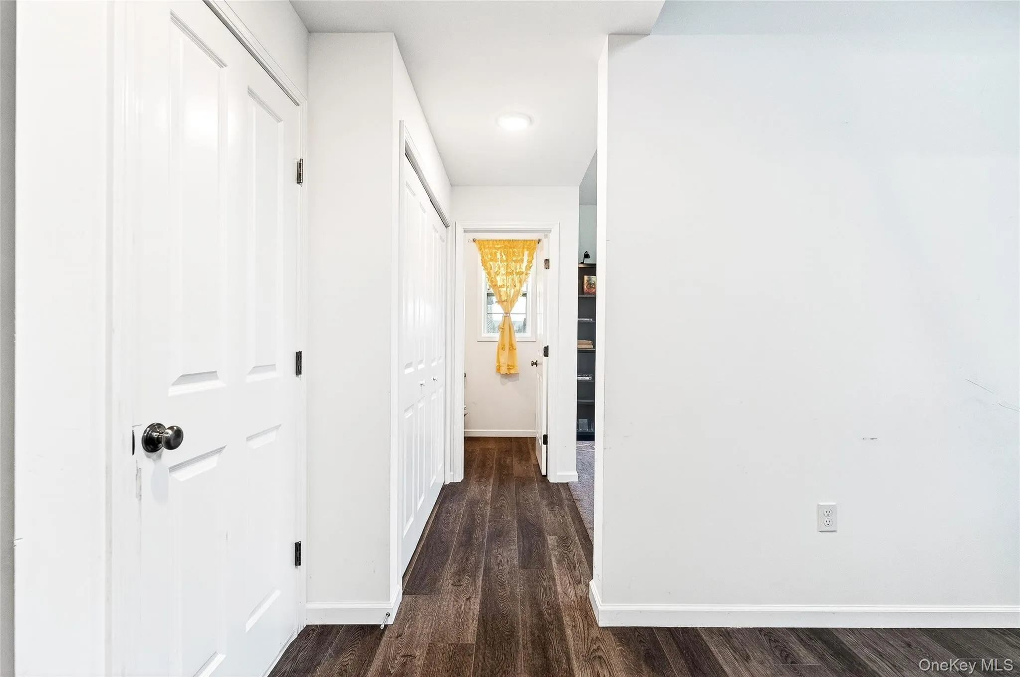 Hall featuring baseboards and dark wood-style flooring Hall featuring baseboards and dark wood-style flooring