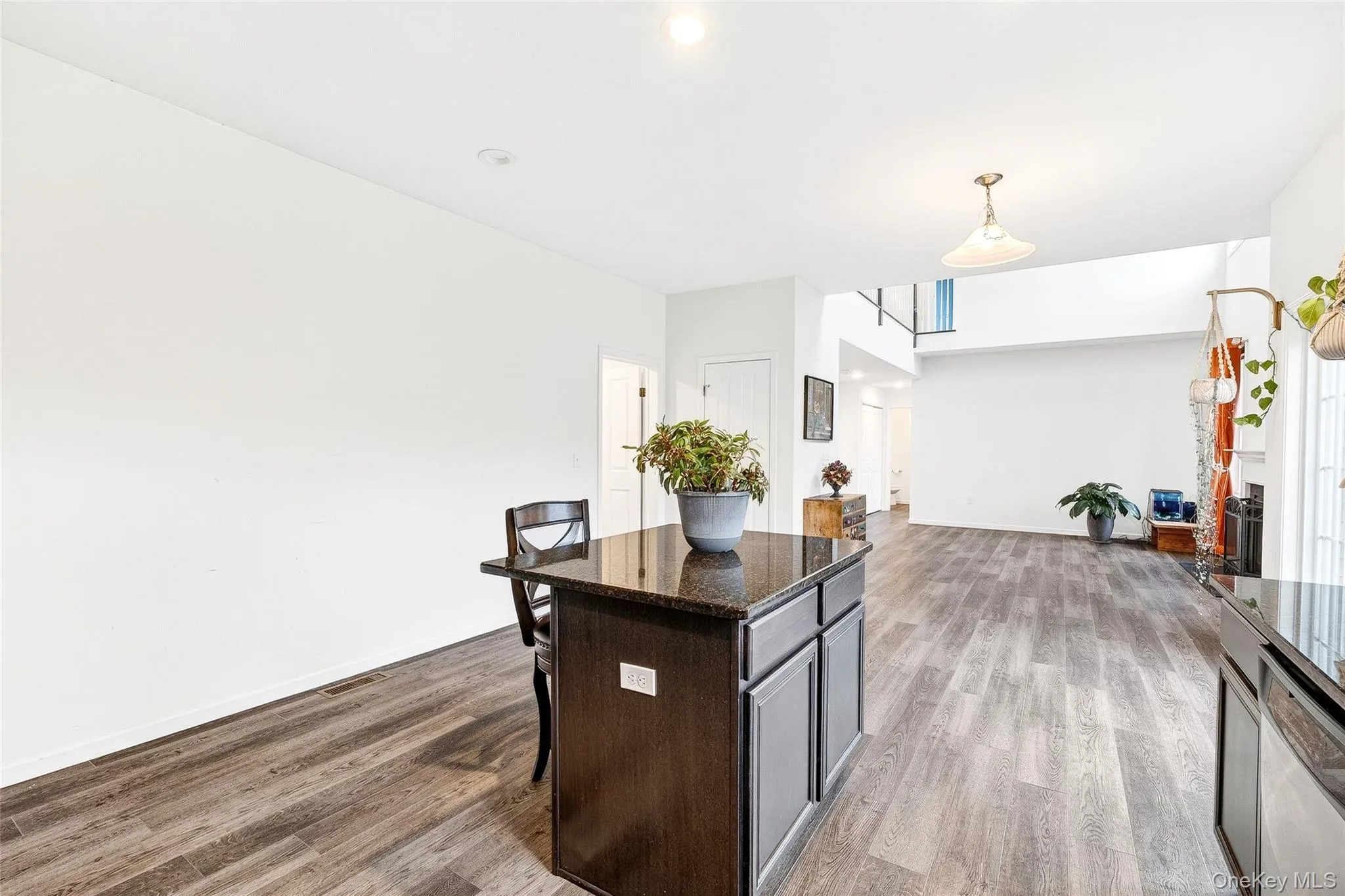 Kitchen with a center island, dark stone counters, a breakfast bar, dark wood-style floors, and hanging light fixtures Kitchen with a center island, dark stone counters, a breakfast bar, dark wood-style floors, and hanging light fixtures
