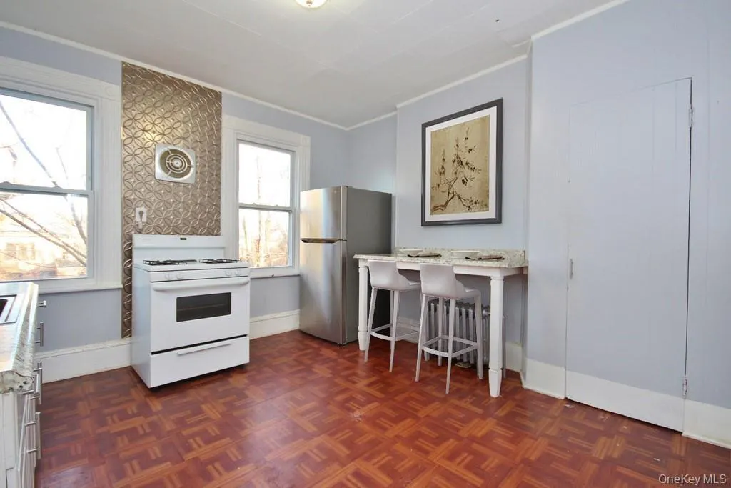 Virtually Staged - Kitchen with white gas stove, freestanding refrigerator, and ornamental molding Virtually Staged - Kitchen with white gas stove, freestanding refrigerator, and ornamental molding