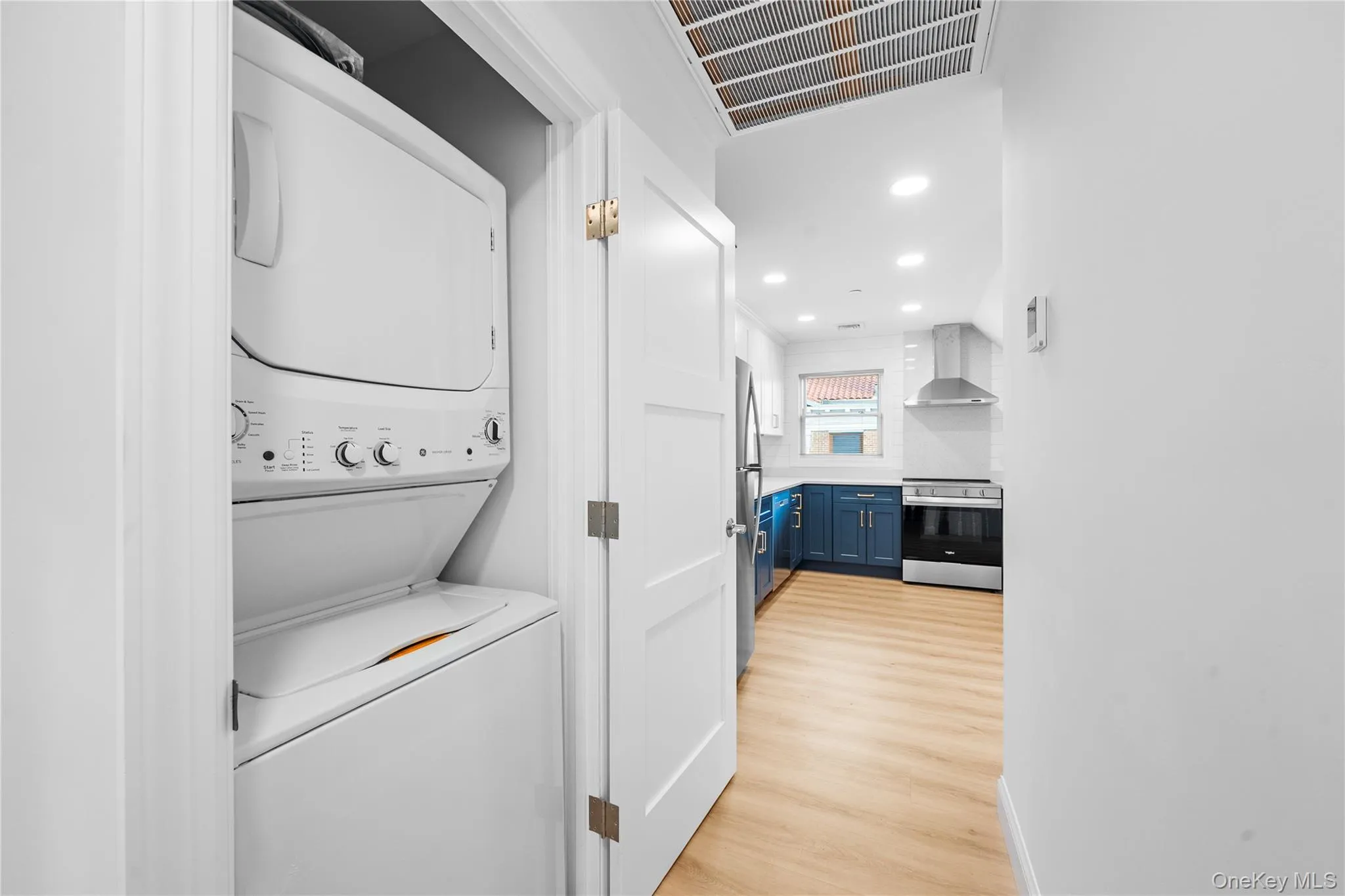 Laundry room featuring estacked washer and dryer, light wood-style flooring, and recessed lighting Laundry room featuring estacked washer and dryer, light wood-style flooring, and recessed lighting