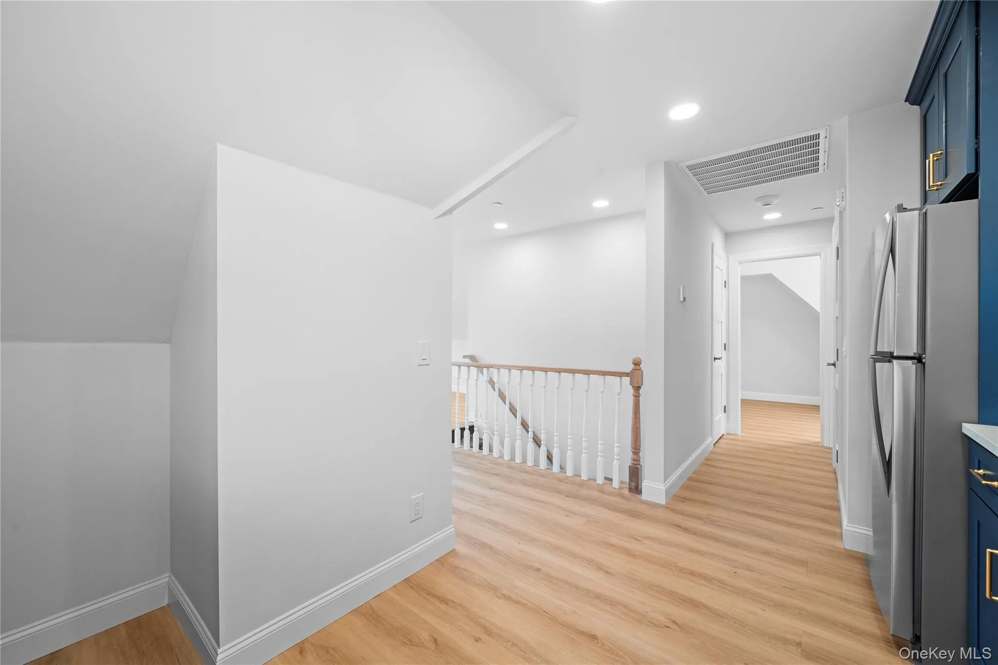 Hallway featuring an upstairs landing, light wood-style floors, and recessed lighting Hallway featuring an upstairs landing, light wood-style floors, and recessed lighting