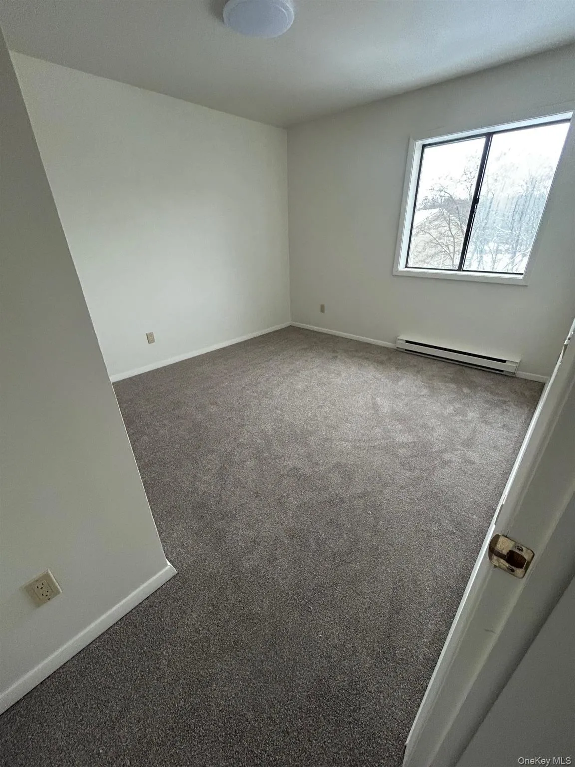 Empty room featuring carpet and a baseboard heating unit Empty room featuring carpet and a baseboard heating unit
