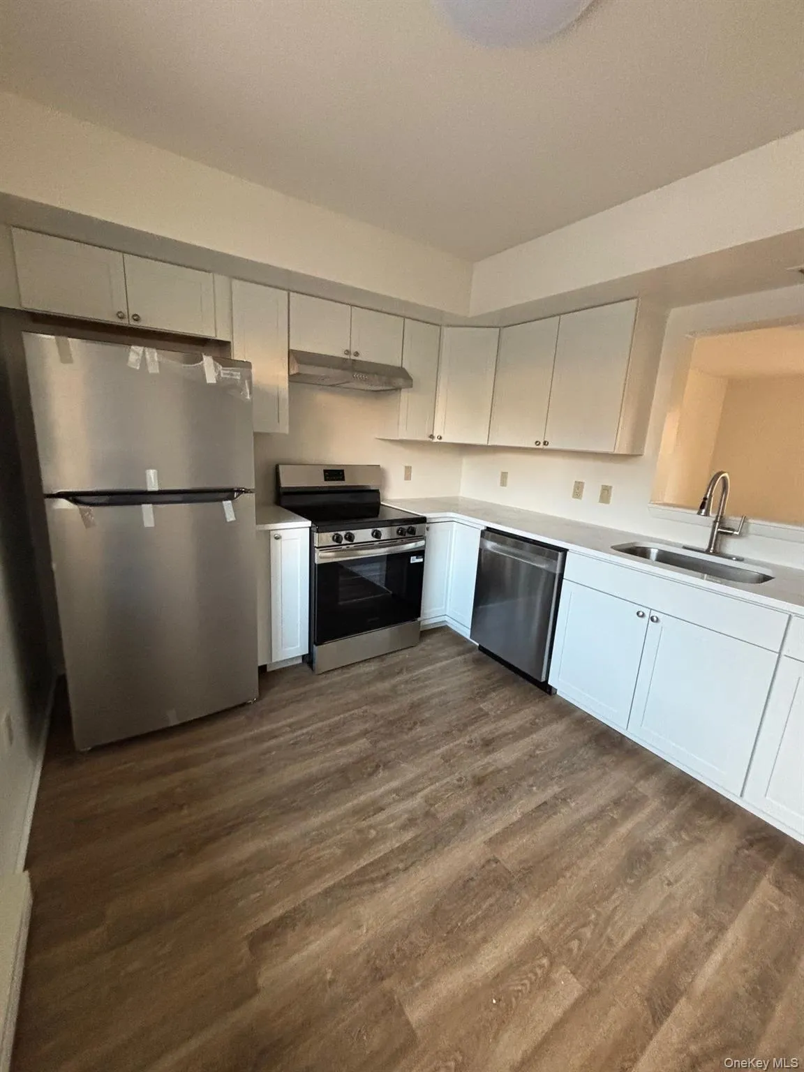 Kitchen with appliances with stainless steel finishes, white cabinetry, and dark wood finished floors Kitchen with appliances with stainless steel finishes, white cabinetry, and dark wood finished floors