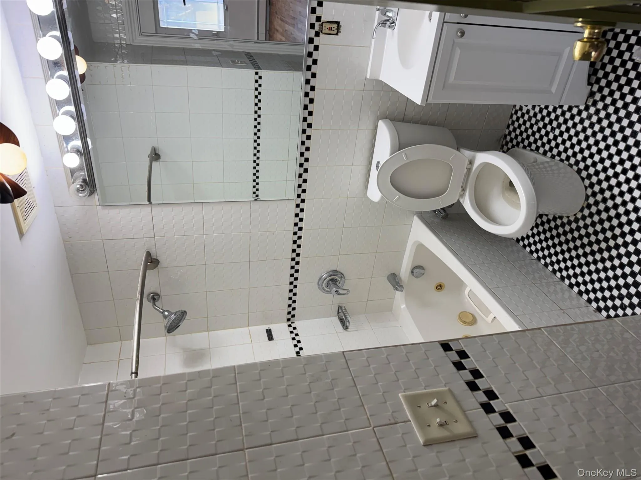 Bathroom featuring tile walls, vanity, a combined bath / shower with jetted tub, and a baseboard radiator Bathroom featuring tile walls, vanity, a combined bath / shower with jetted tub, and a baseboard radiator