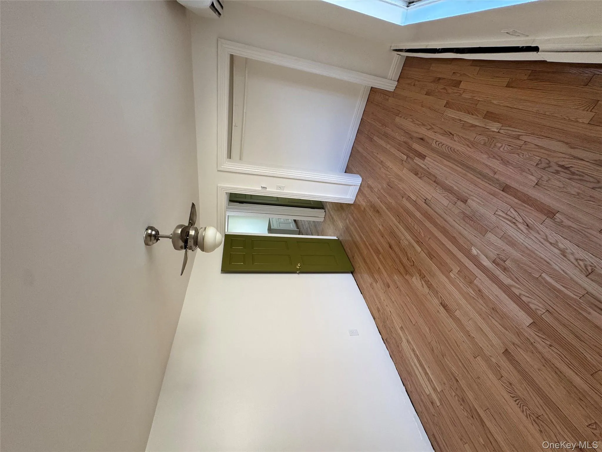 Unfurnished bedroom featuring light wood-style floors, ceiling fan, a closet, and a wall unit AC Unfurnished bedroom featuring light wood-style floors, ceiling fan, a closet, and a wall unit AC